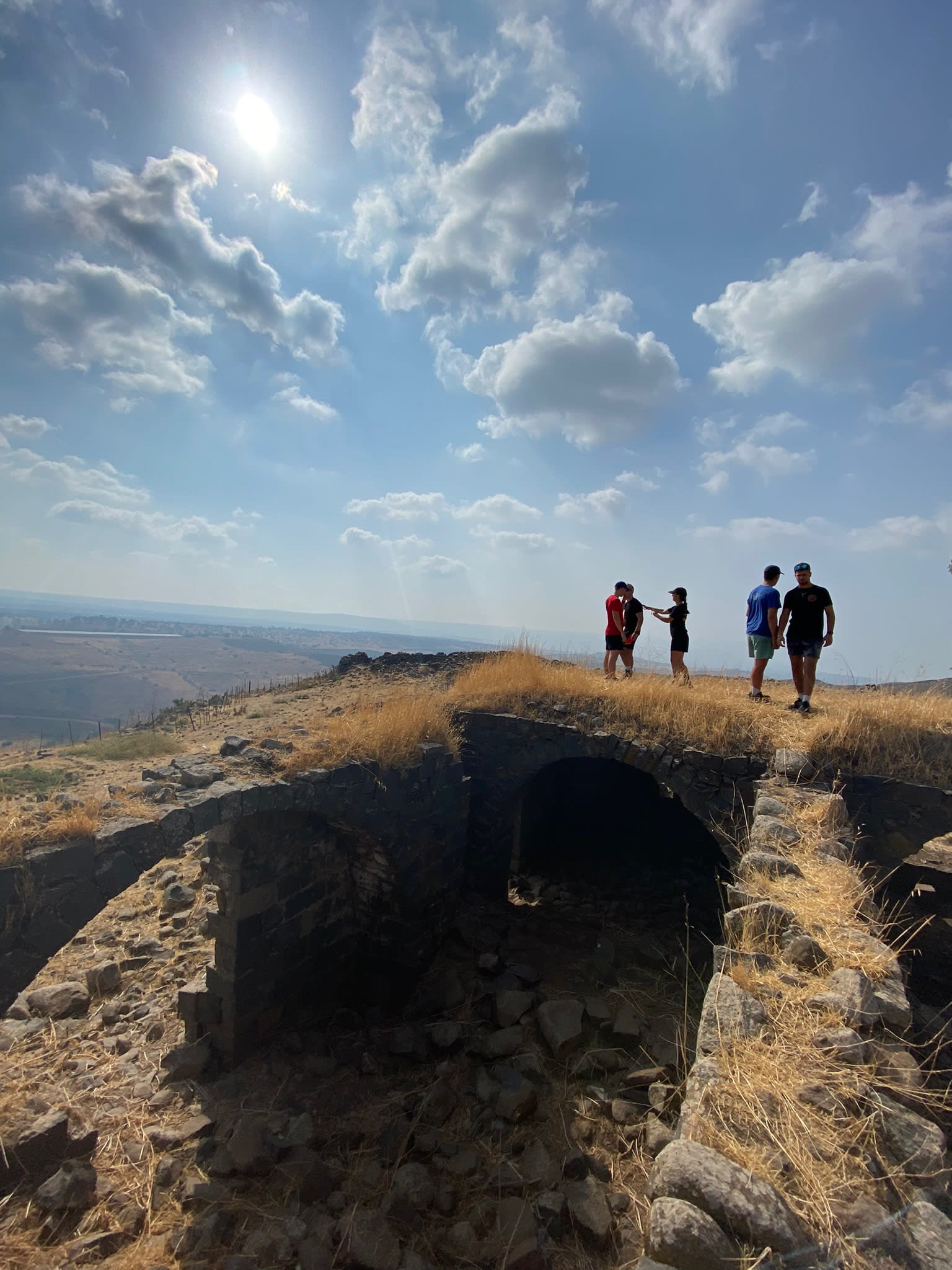 Participants looking into the distance on the peak of a mountain in the dessert.