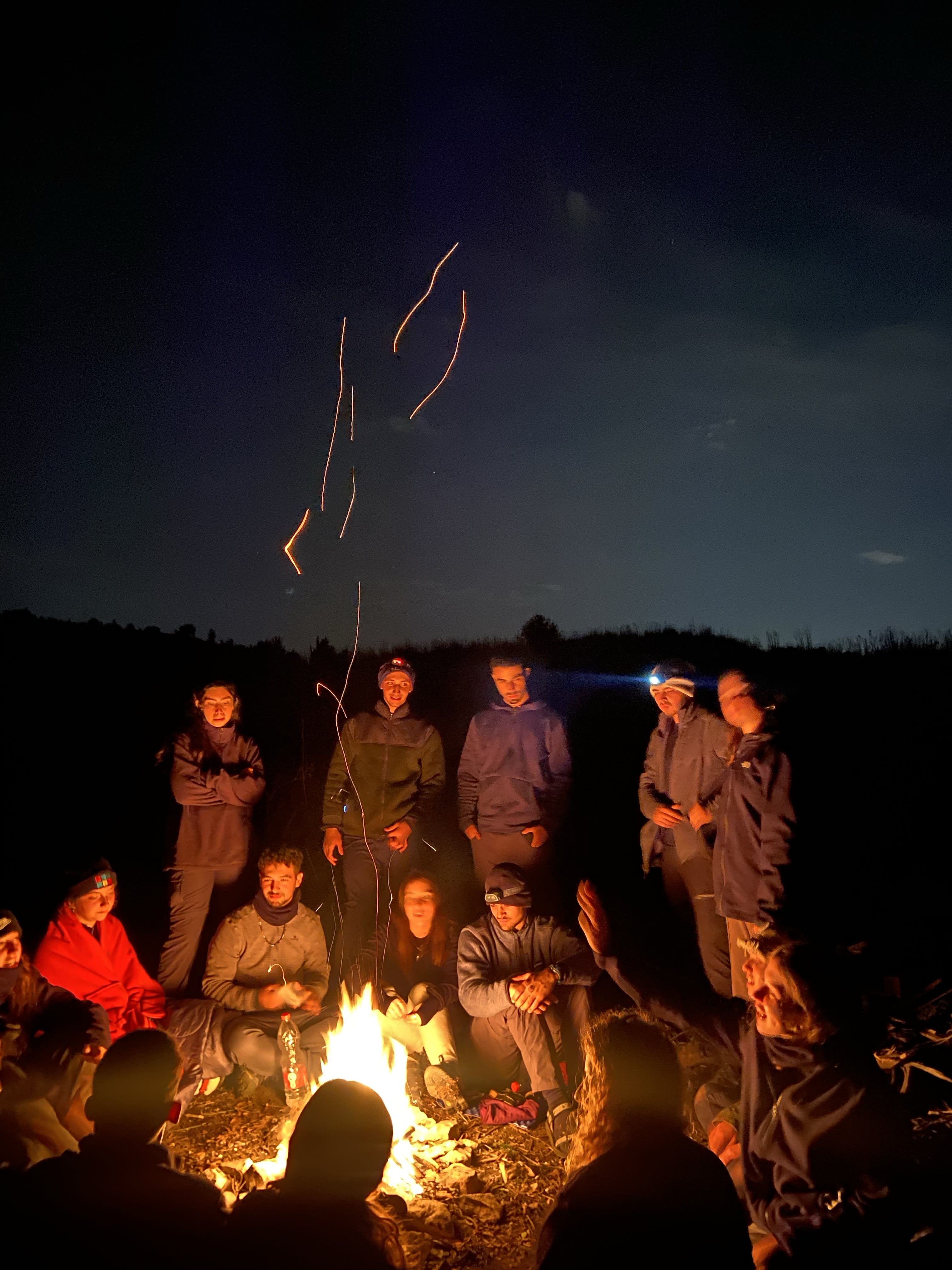 Mechina participants standing in a circle in the dessert with hiking backpacks on the ground.