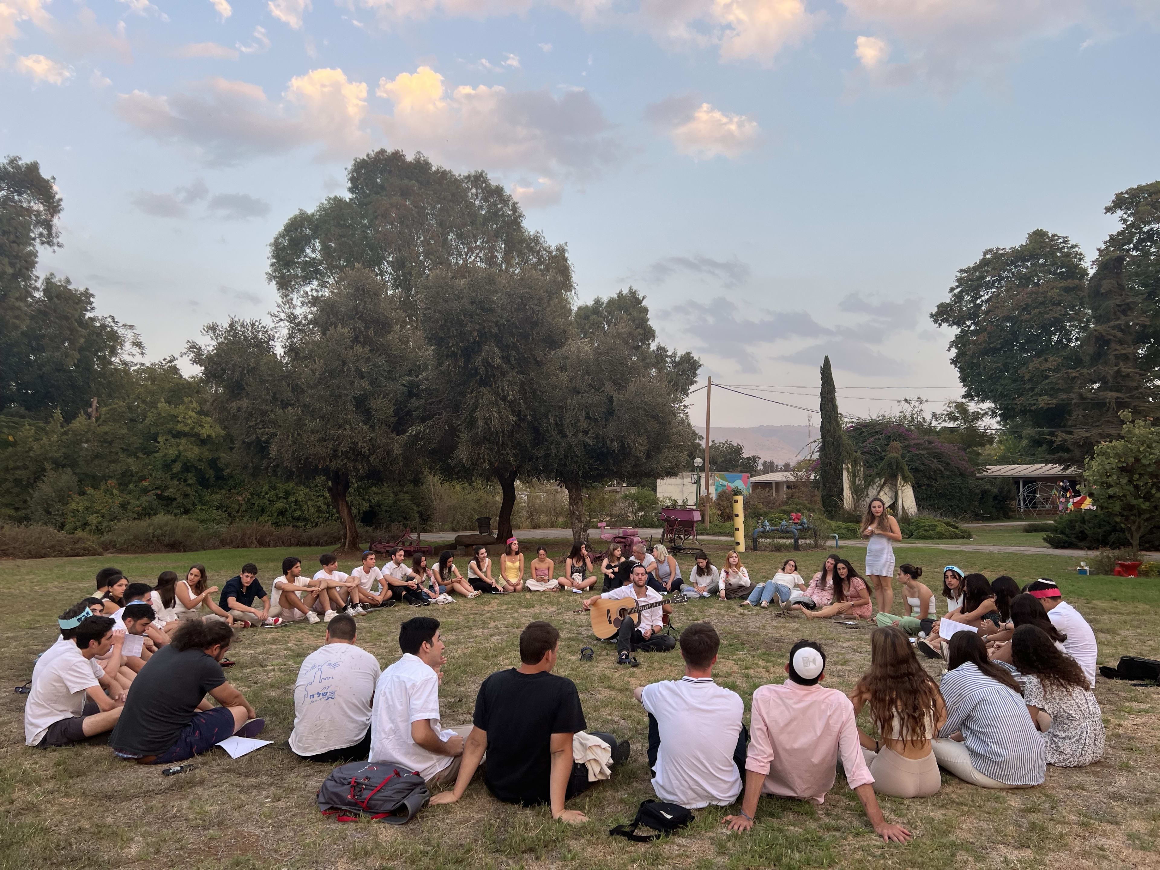 Mechina participants sitting in a circle on the grass