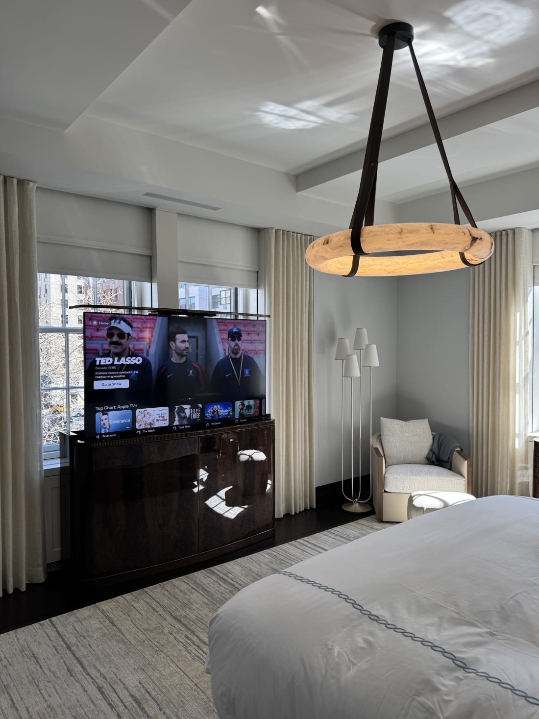 Luxury New York apartment bedroom with smart lighting motorized shades and wall mounted television