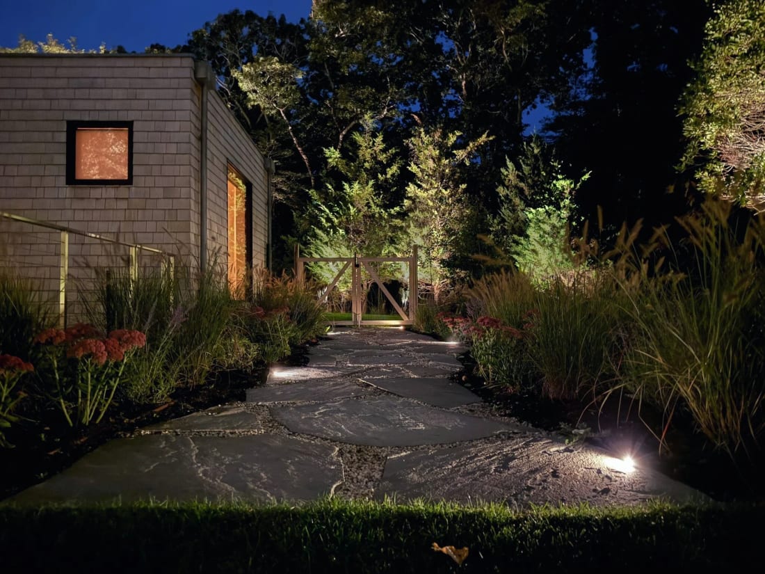 Warm pathway lighting guiding movement through landscaped grounds at night