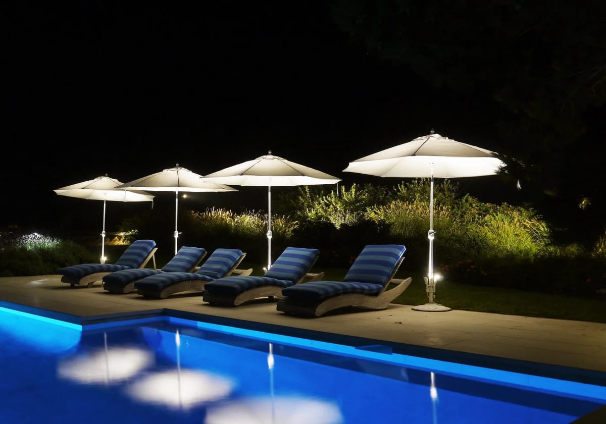 Poolside landscape lighting illuminating planted edges and outdoor seating after dark