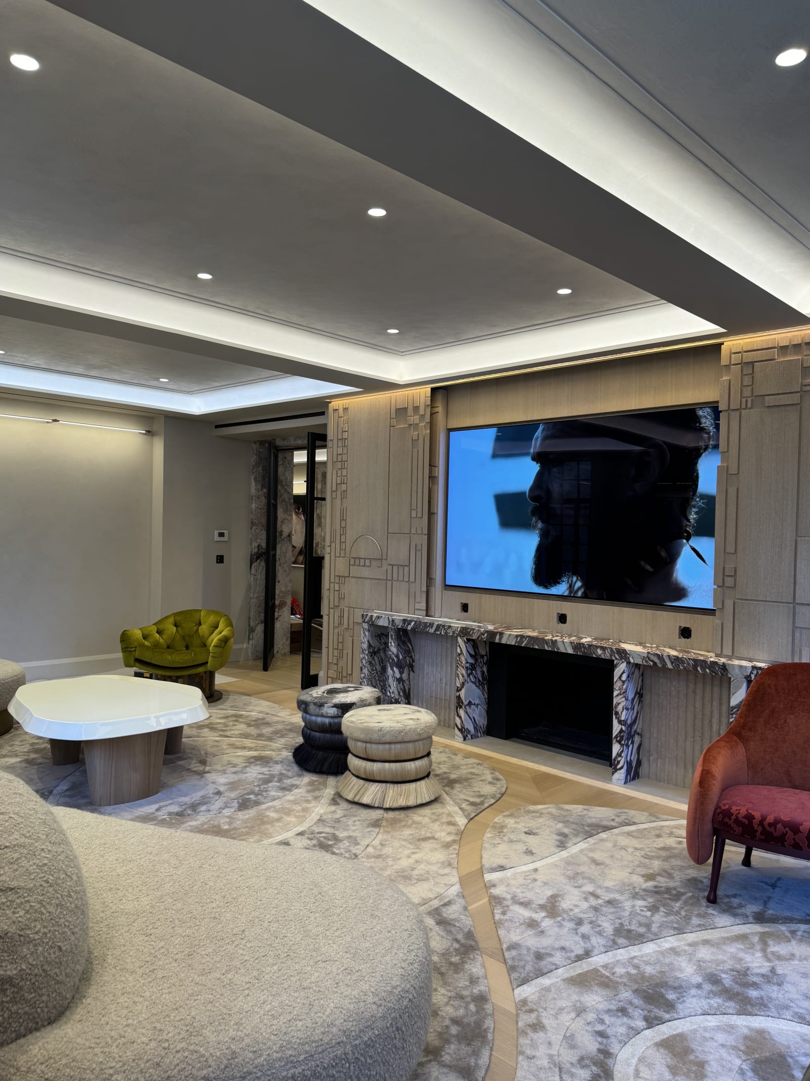 Custom media room with a large integrated display, recessed lighting, and tailored seating