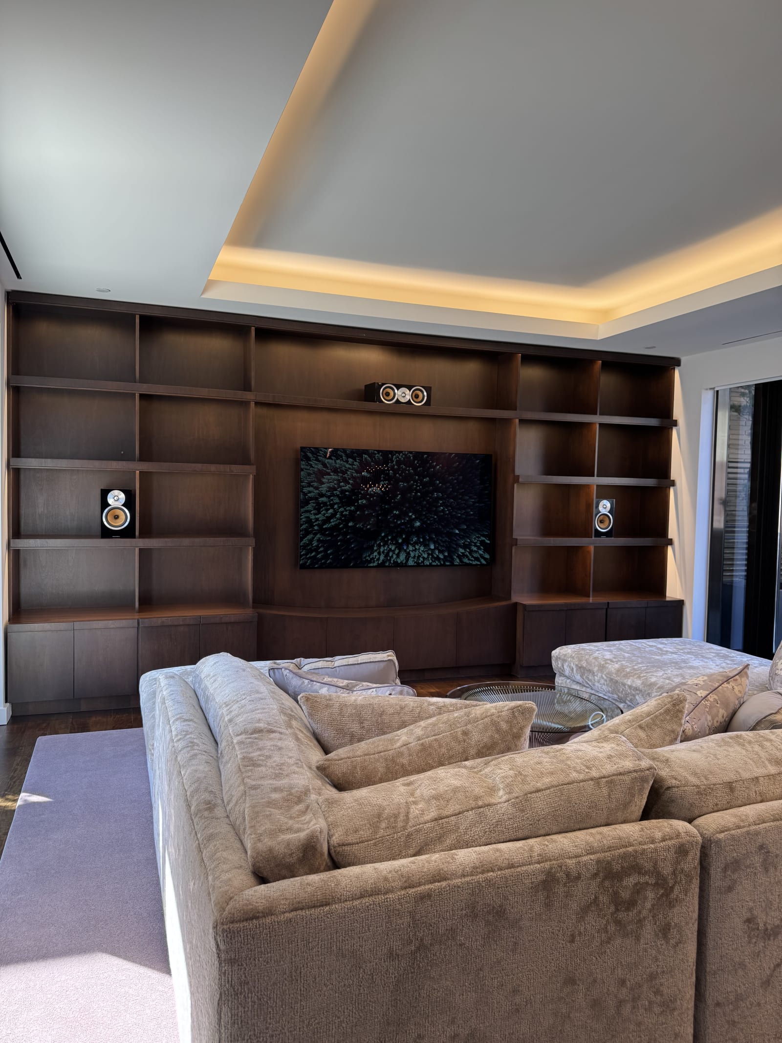 Luxury media room with integrated television, architectural speakers, and custom cabinetry