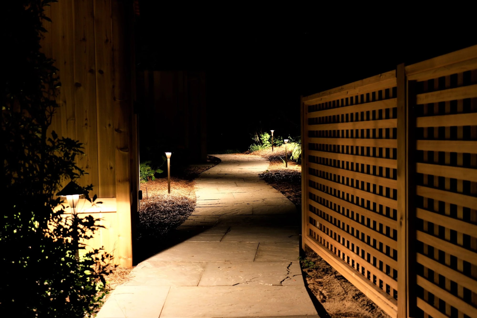 Warm pathway lighting guiding movement through a Hamptons garden at night