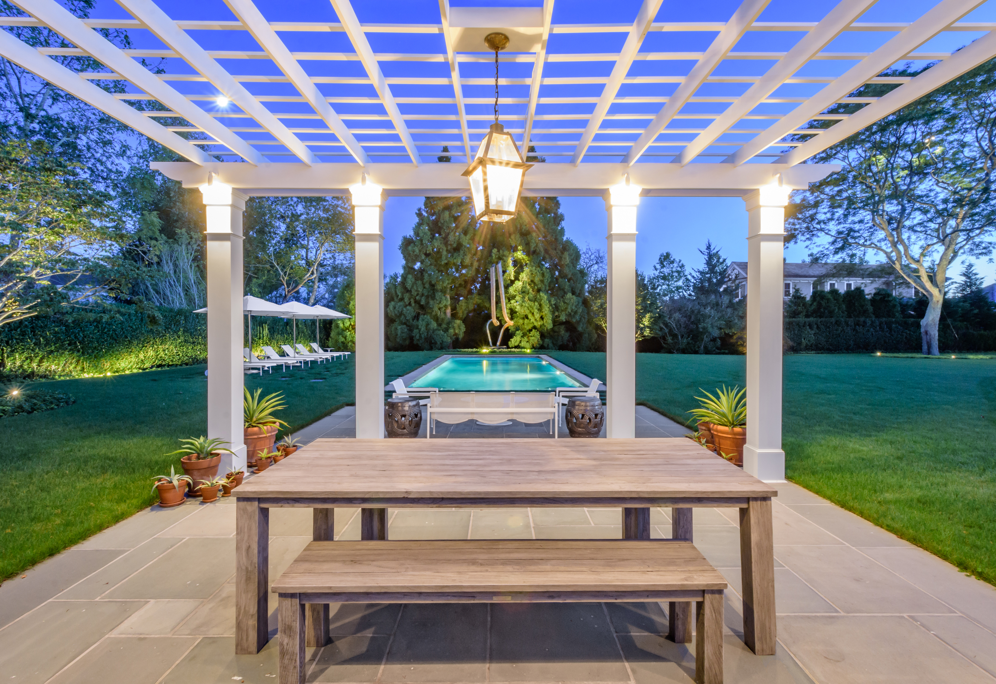 Refined landscape lighting for luxury backyard with trees and architectural outdoor spaces