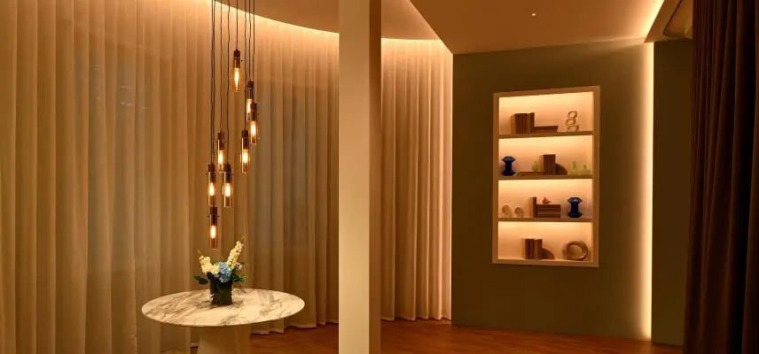 Warmly lit interior with motorized drapery framing a dining and lounge area