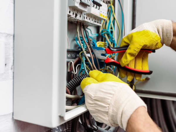 Électricien partenaire intervenant sur un appareillage électrique mural