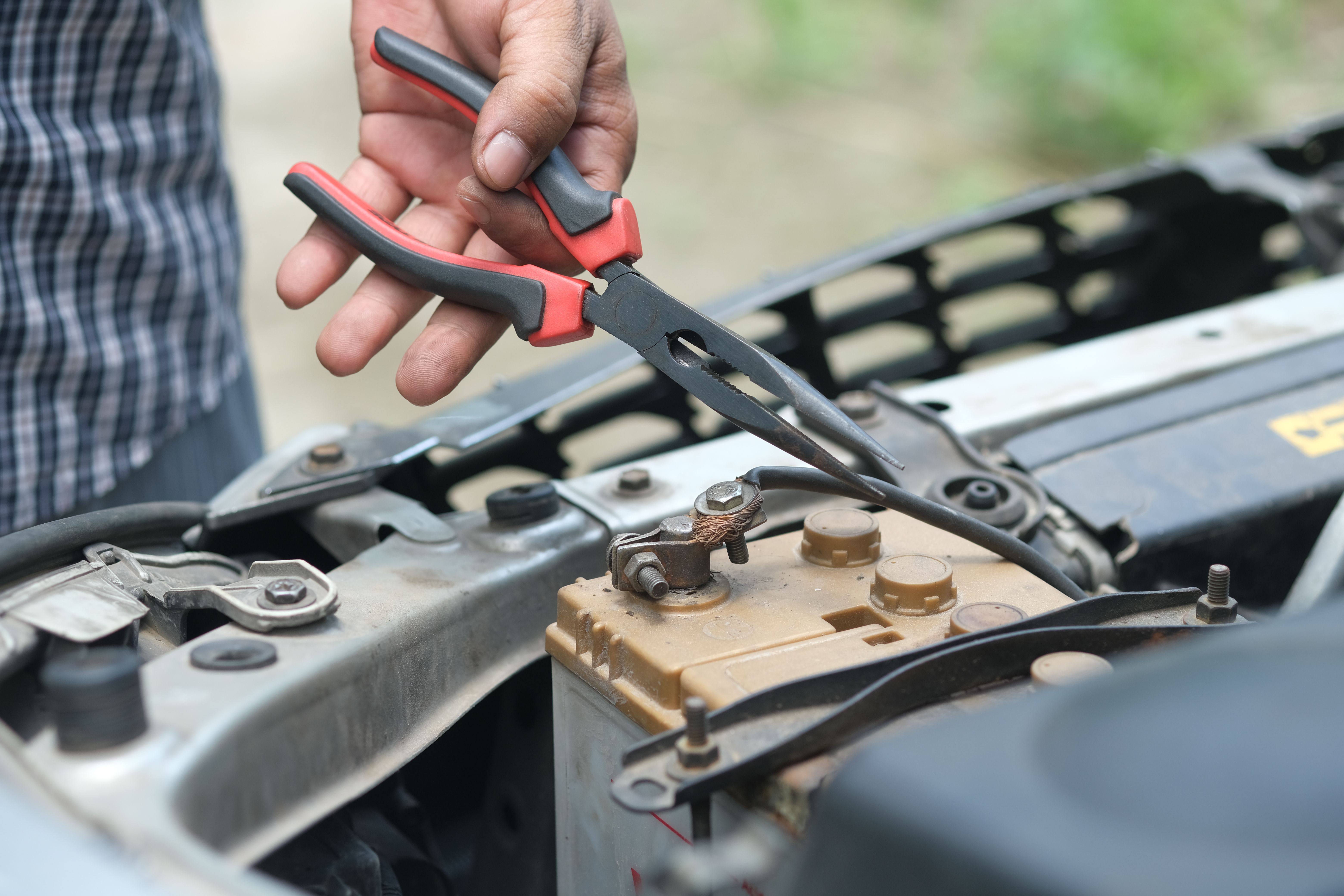 mechanic checking battery under car hood