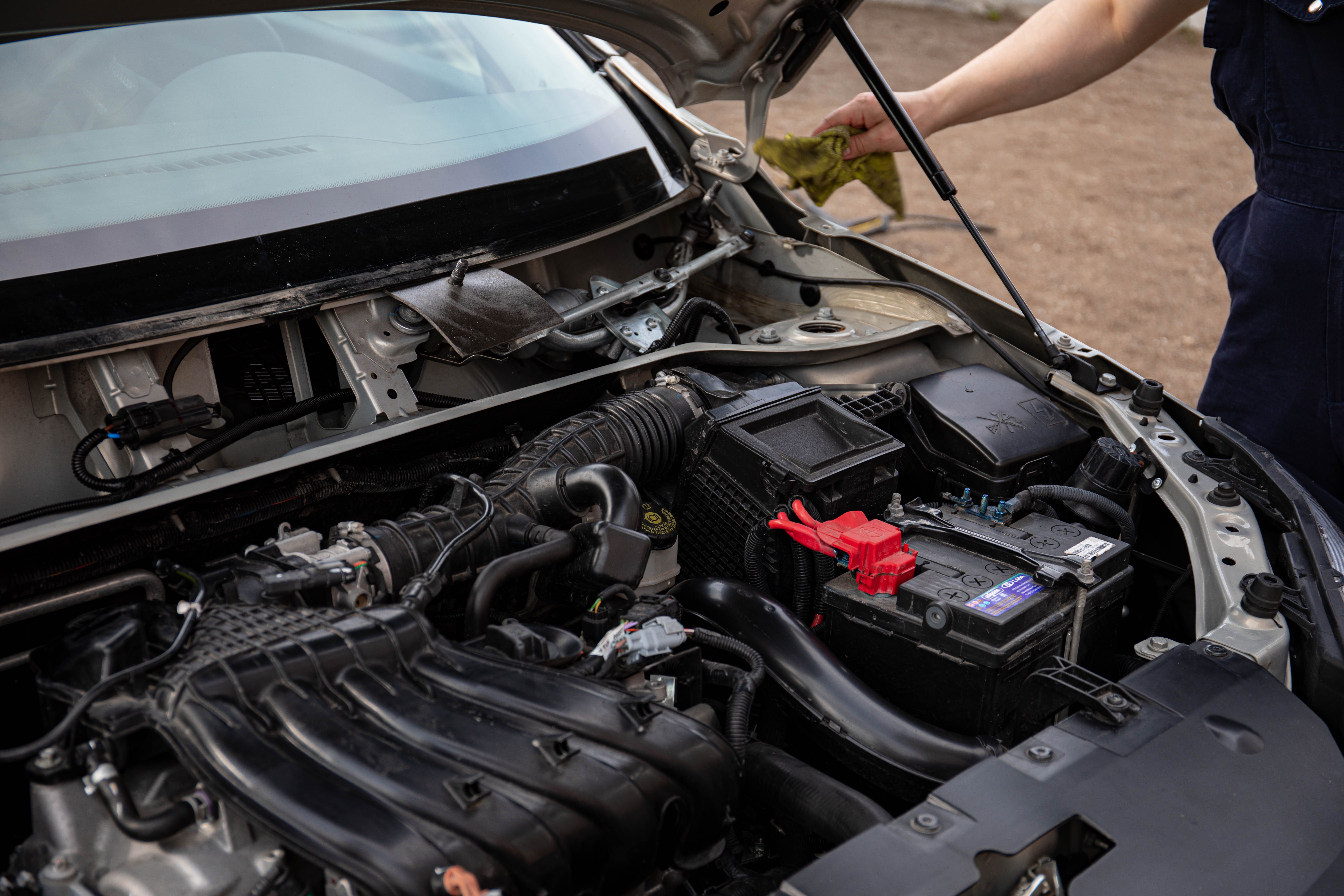 mechanic testing car battery multimeter