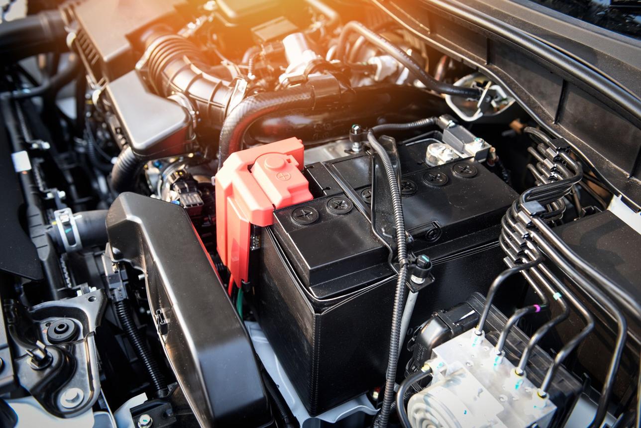 Car battery beneath an open bonnet on a sunny summer day