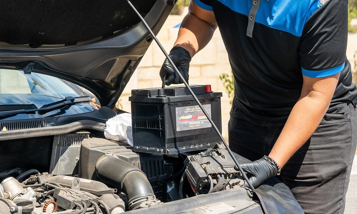 Mechanic installing a replacement car battery in an automotive workshop