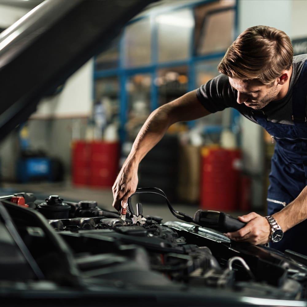 Automotive technician inspecting a car charging system after a battery warning light appears