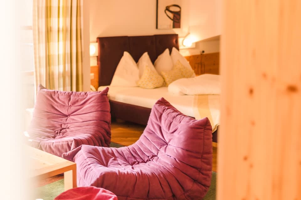Cozy interior of Glemmtalerhof in Hinterglemm with purple chairs and a comfortable bed, inviting relaxation.