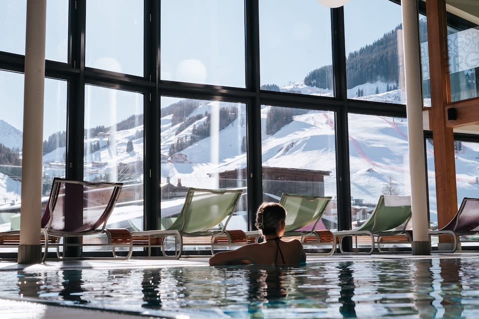 A serene scene at Glemmtalerhof in Hinterglemm, showcasing a relaxing pool with snowy mountains in the background.