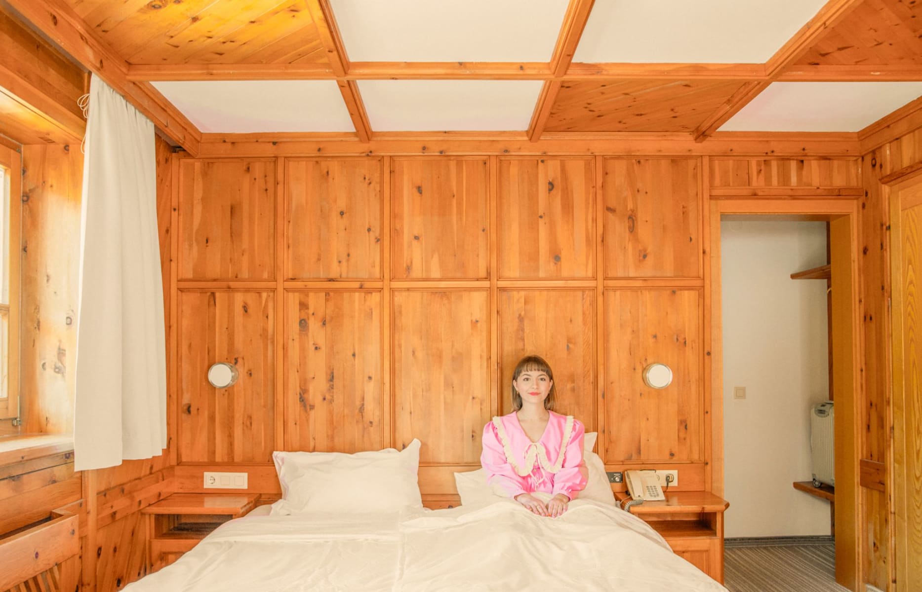Ein Zimmer im Glemmtalerhof mit warmen Holzdetails und einer Frau auf dem Bett.