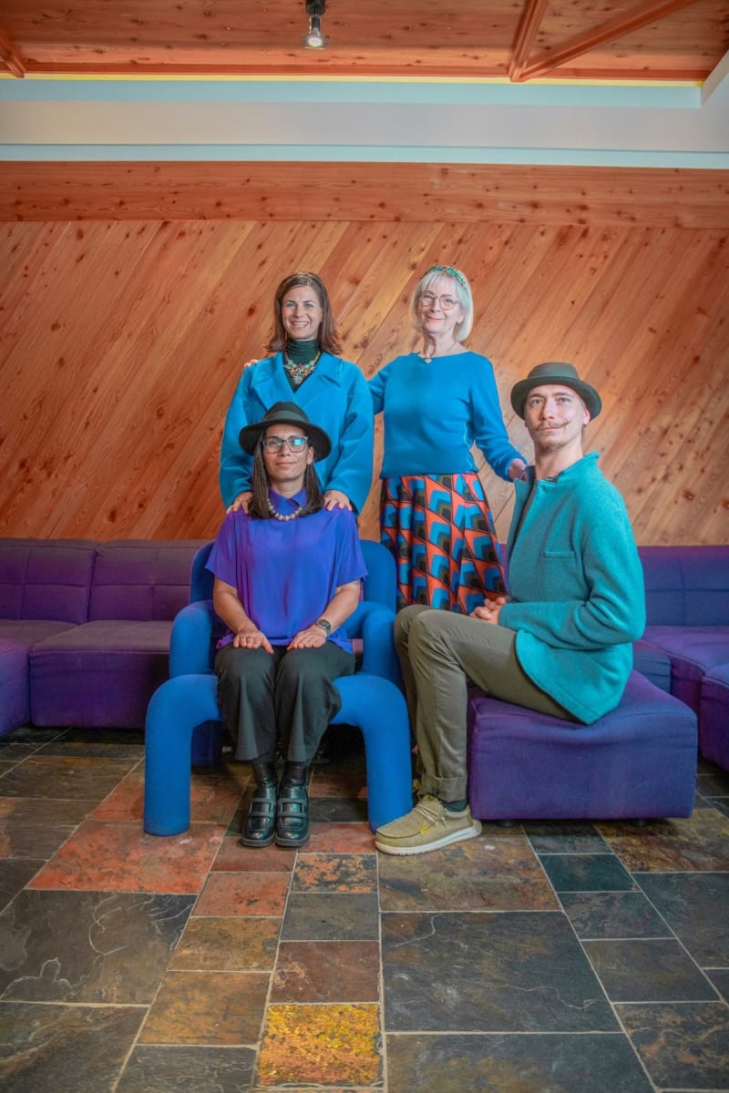 A group of four people poses together in a colorful setting, evoking the vibrant spirit of Hinterglemm.