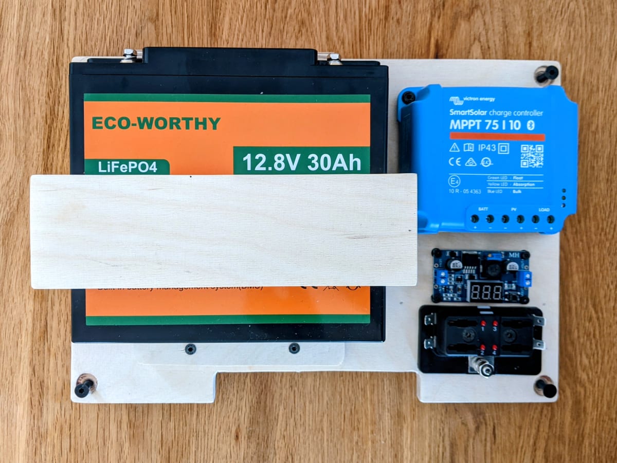Battery, solar charge controller, fuse holder and buck converter mounted on the base plate.