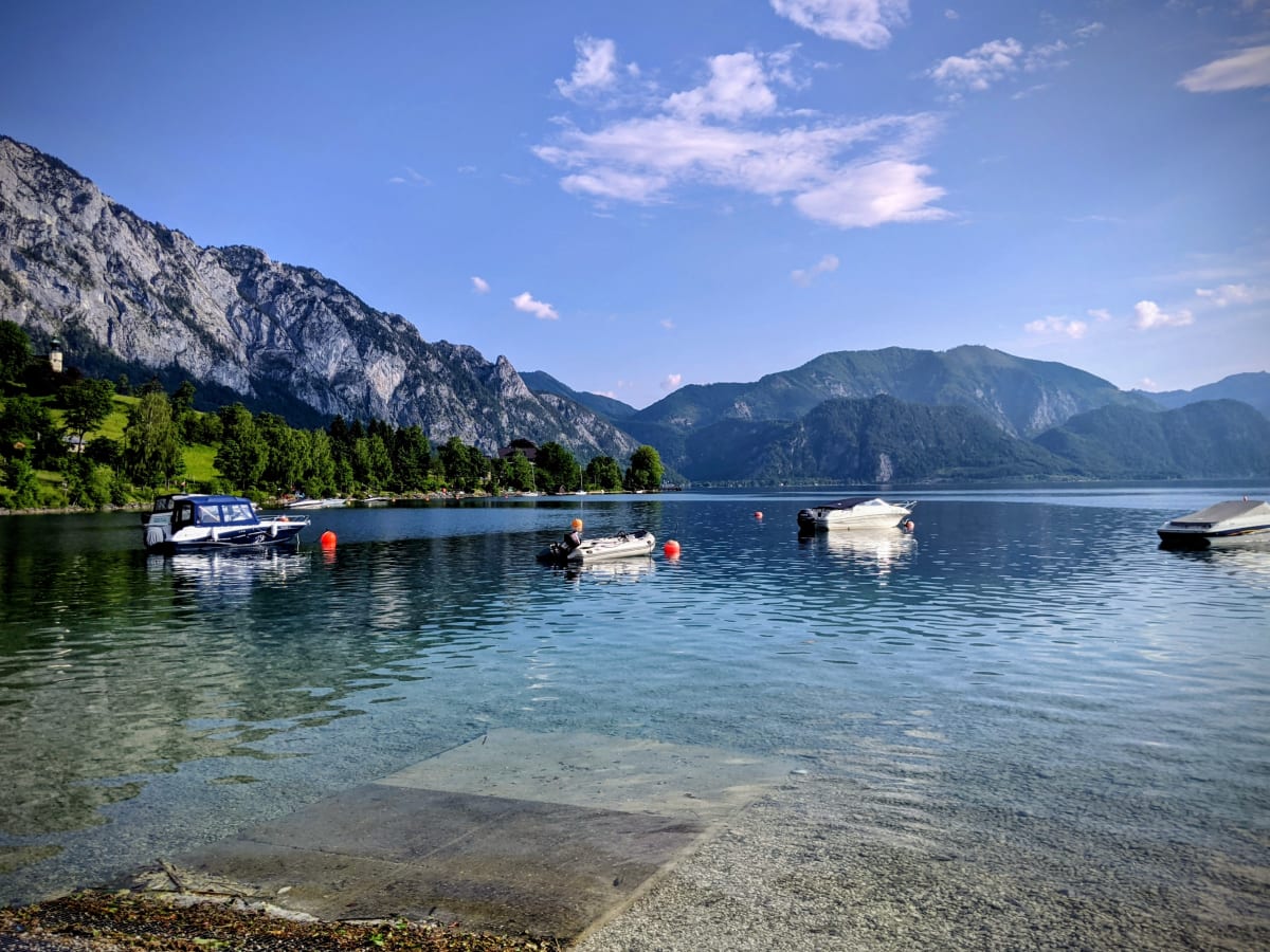 Blick vom Campingplatz auf den Attersee mit umliegenden Bergen.