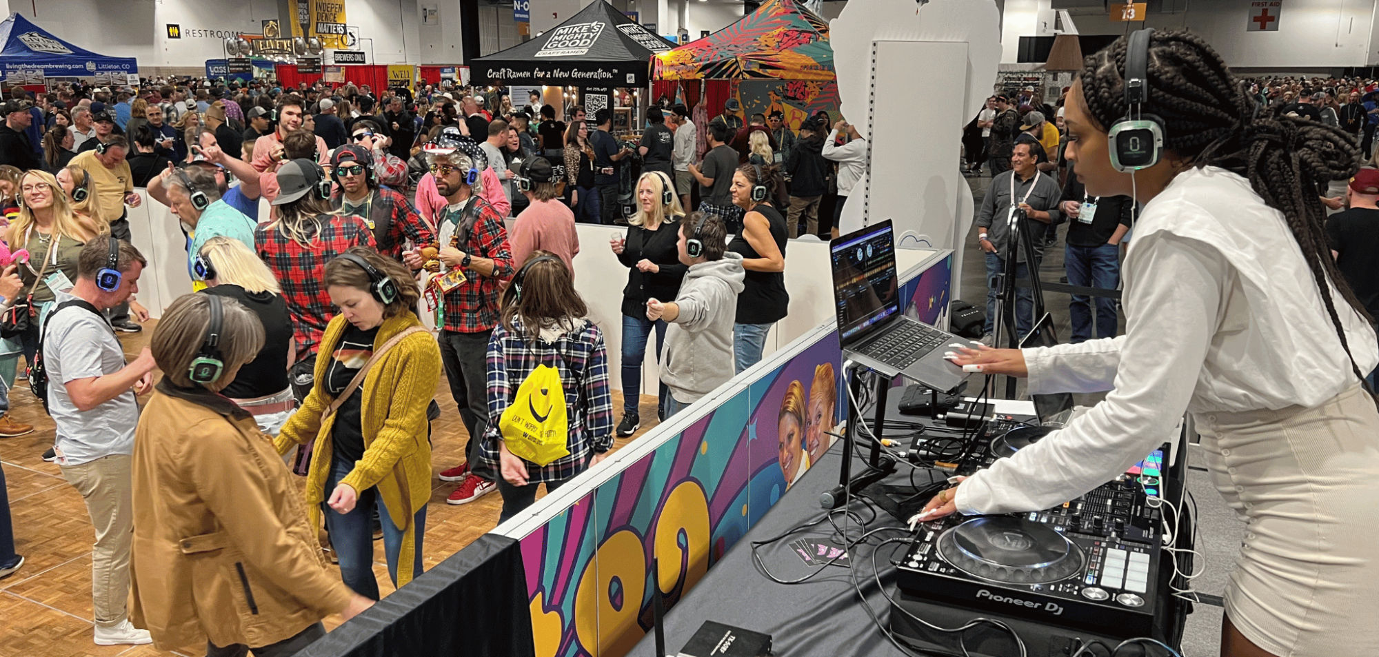 Large indoor festival with a sea of people enjoying silent disco DJ.