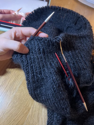 Closeup of the bind-off just started, with a video tutorial visible on an iPad in the background