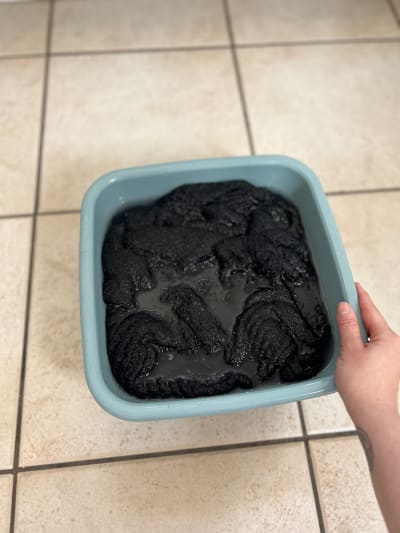 The sweater in a small tub of warm soapy water