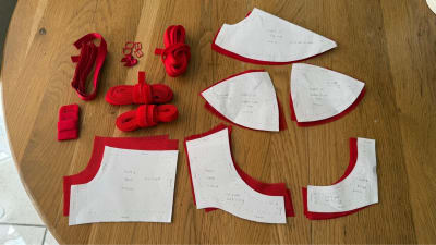 Final draft pattern pieces laid out with red bra-making notions: elastics, rings, sliders, and hook-and-eye