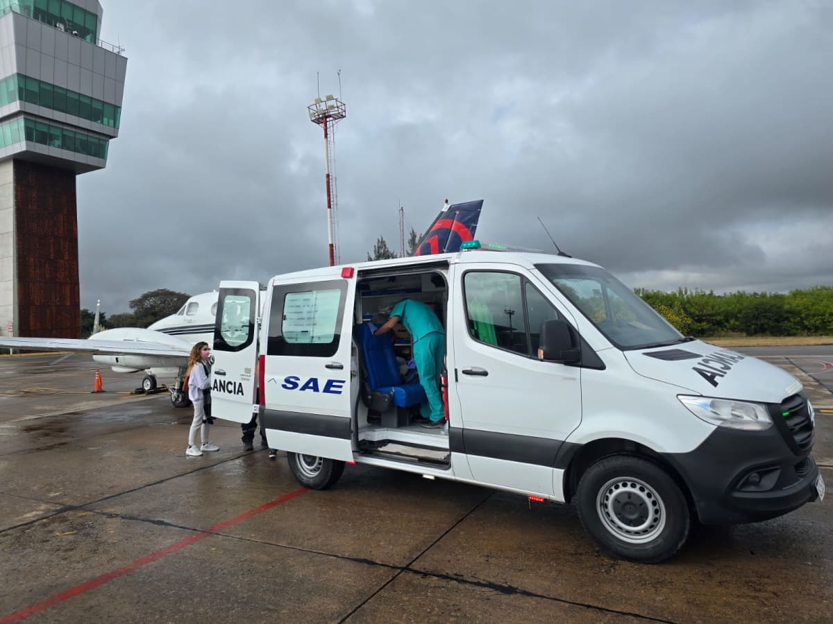 Ambulancia SAE junto a avión en pista de aeropuerto