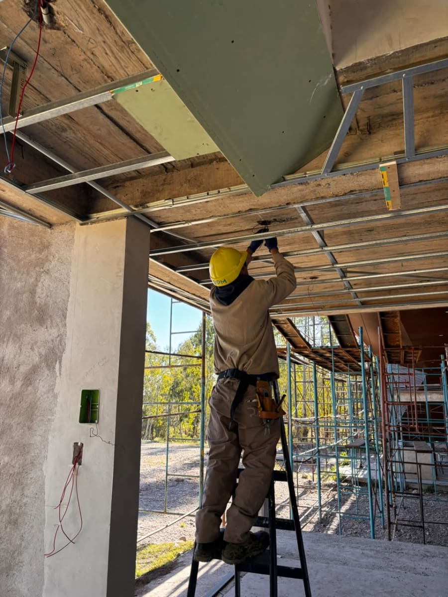 Operario de RPM Construcciones instalando el cableado en el cielorraso de uno de los módulos del pórtico