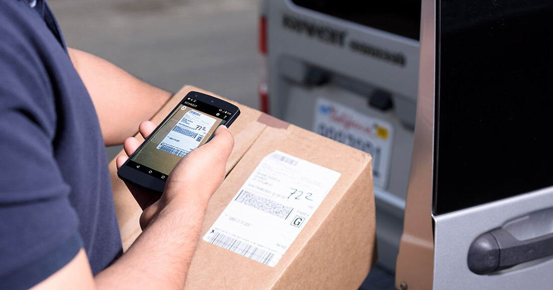 Warehouse worker with mobile app scanning bar code for stock control