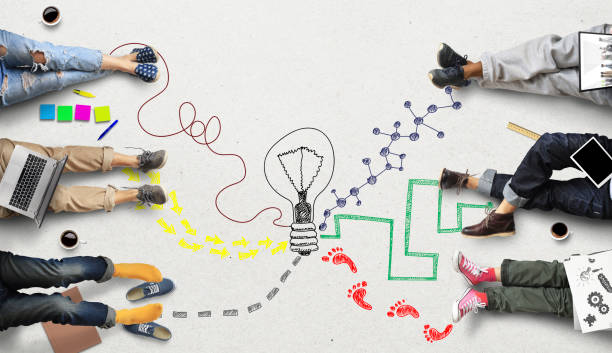 Drawing of a lightbulb on the floor surrounded by people with laptops and sketch pads