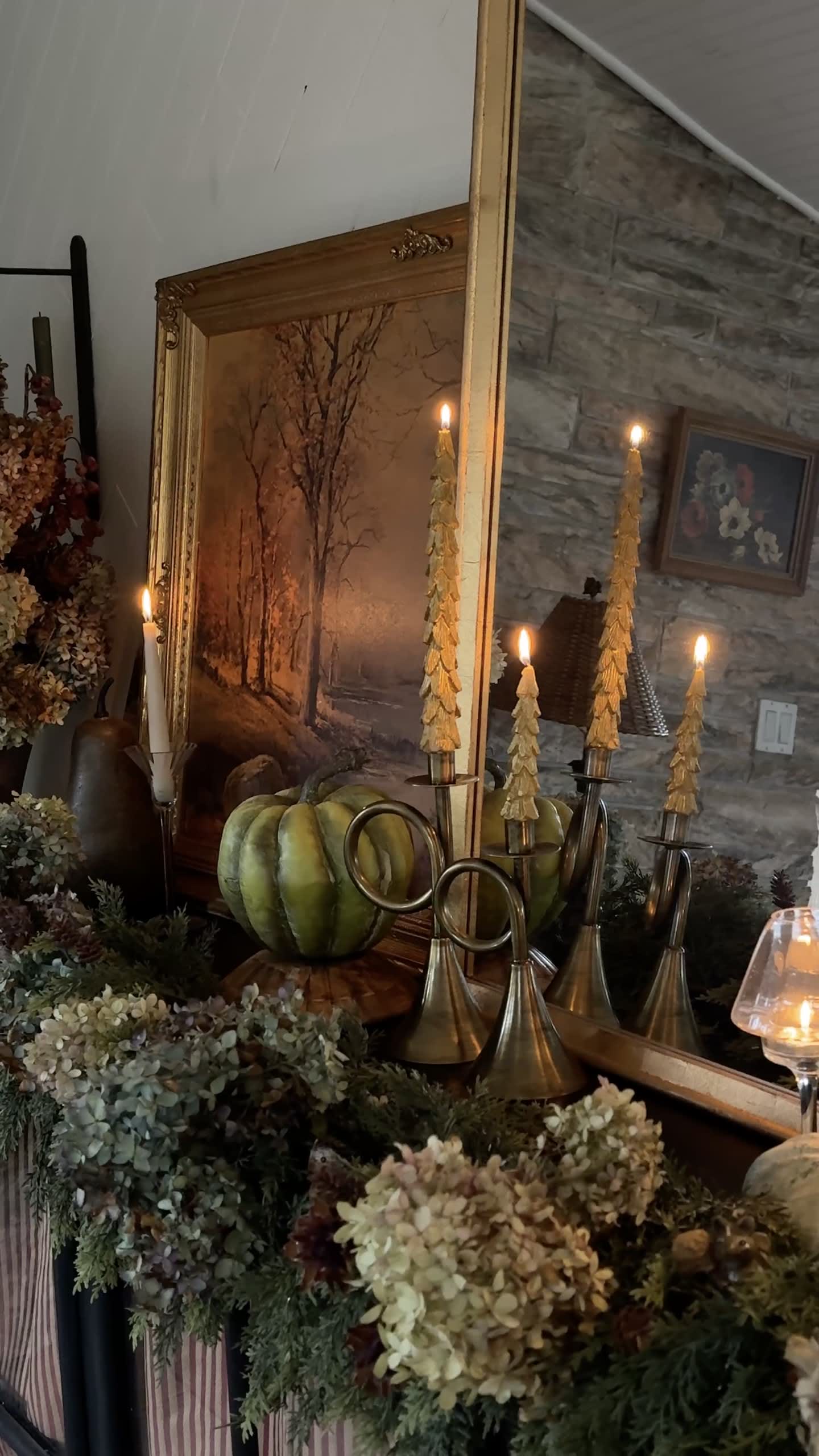 Fall mantel with brass candlesticks, pumpkins, and dried florals