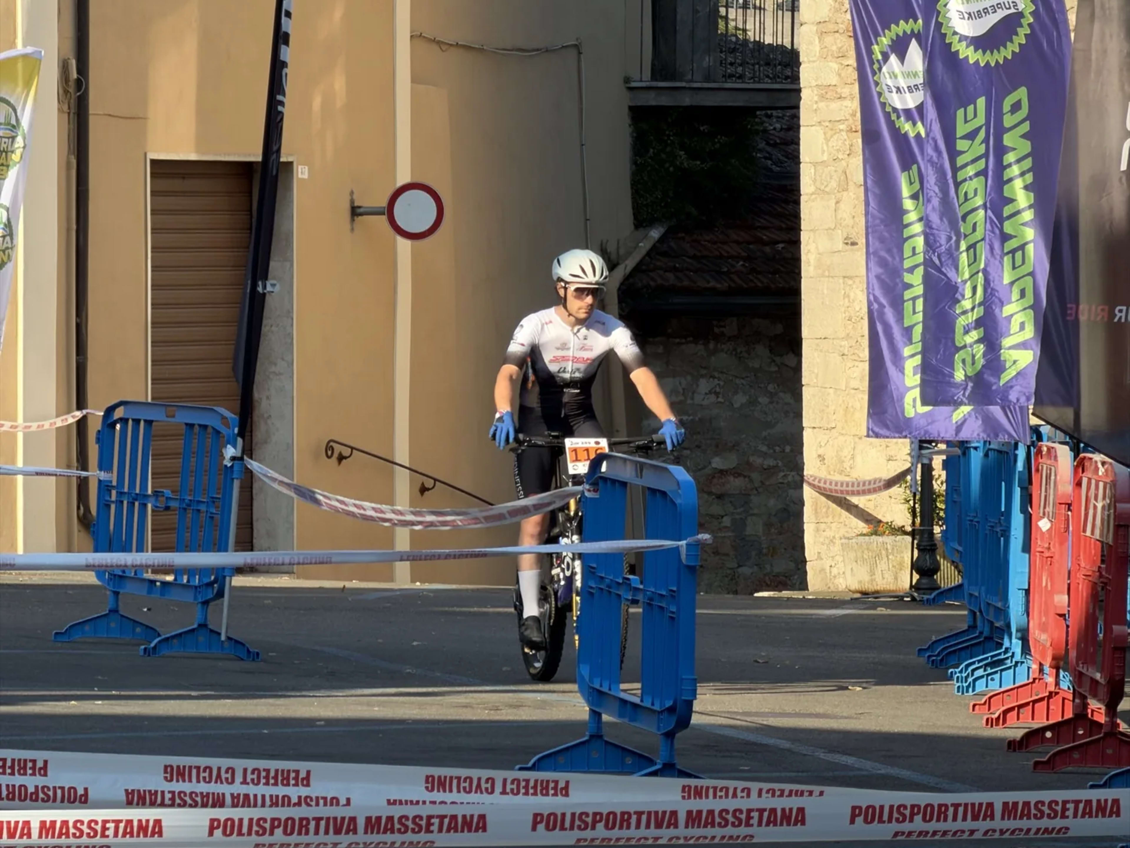 Atleta in attesa sotto lo striscione Partenza tra le transenne del borgo