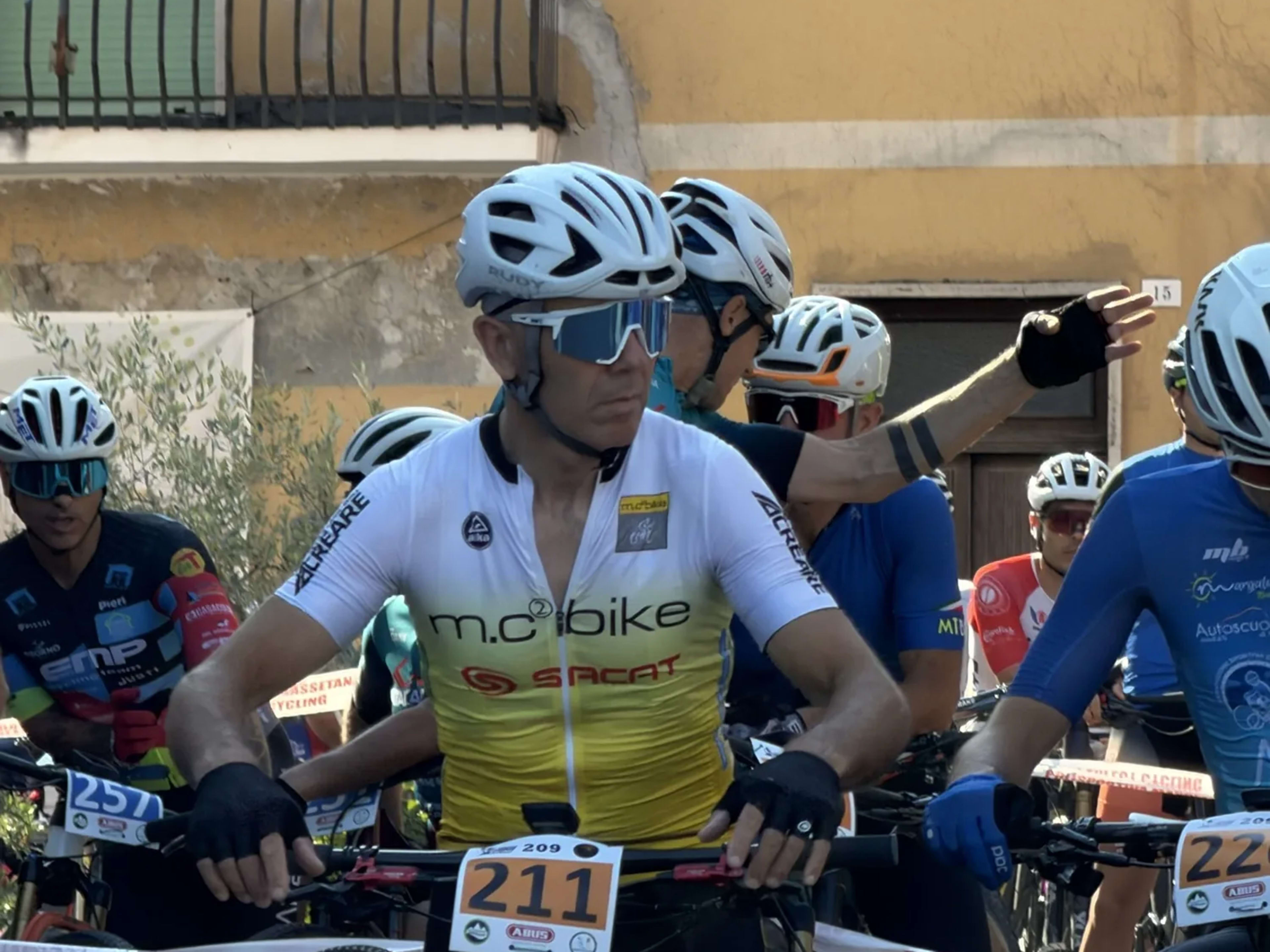 Biker concentrato in sella in prima fila dietro il nastro di partenza
