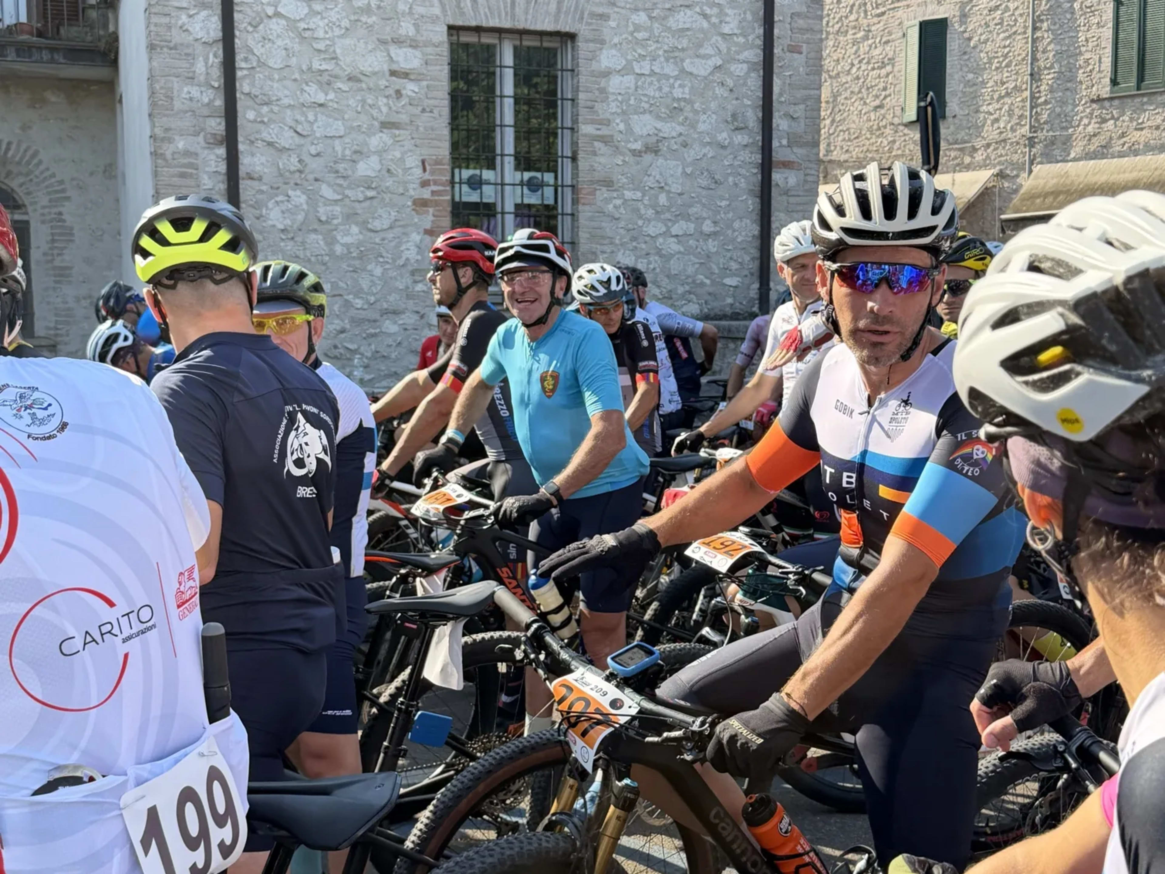 Gruppo di bikers schierati in piazza tra le case in pietra prima del via