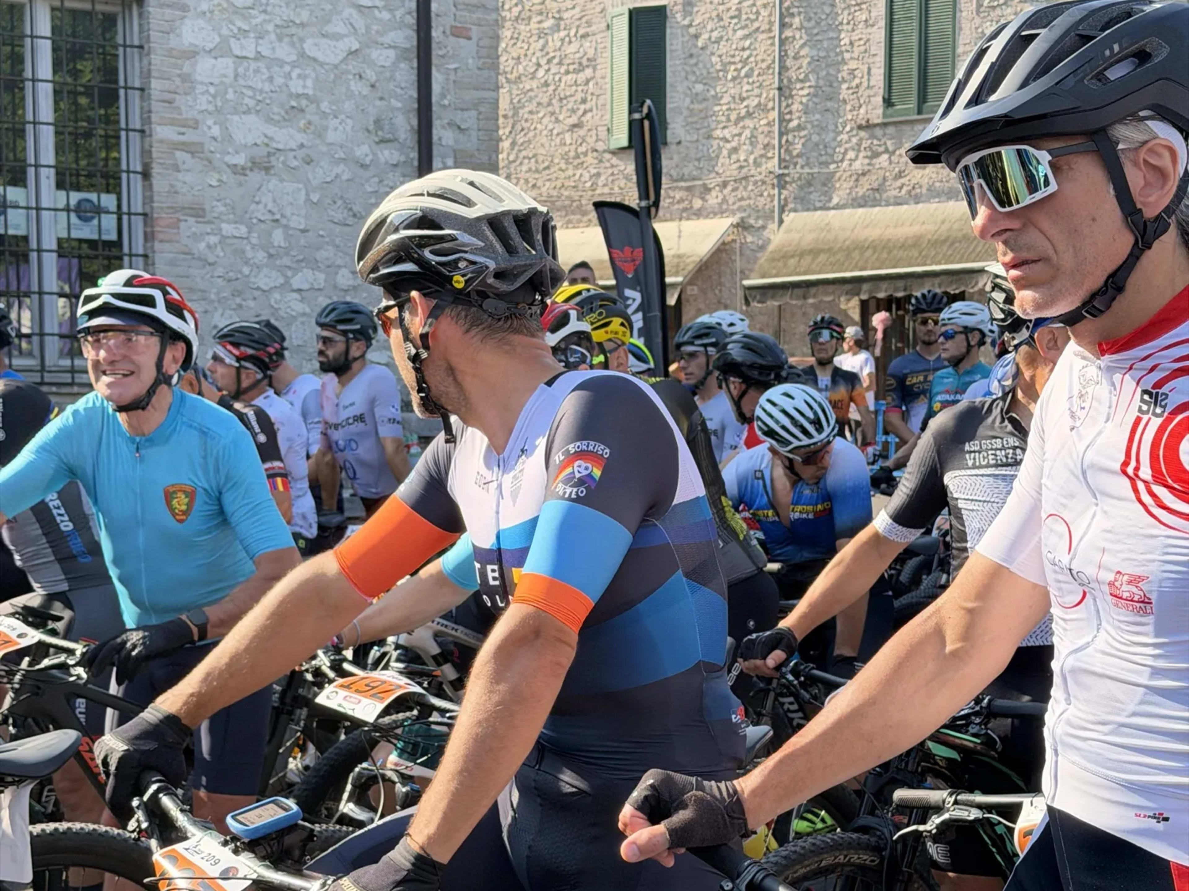 Atleti pronti al via nella zona partenza, bici allineate nel centro storico