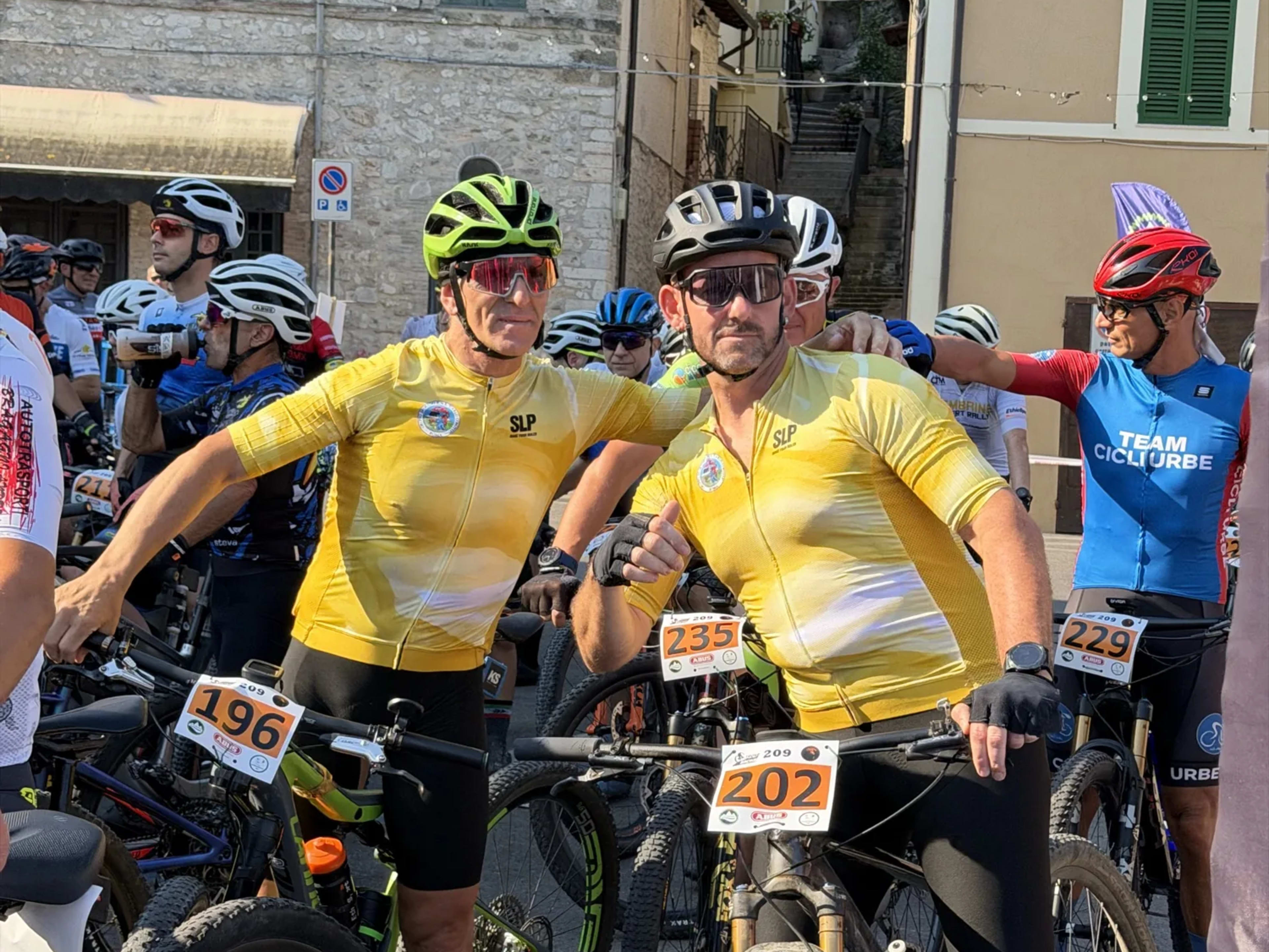 Due bikers in maglia gialla posano prima del via tra i vicoli di Arrone