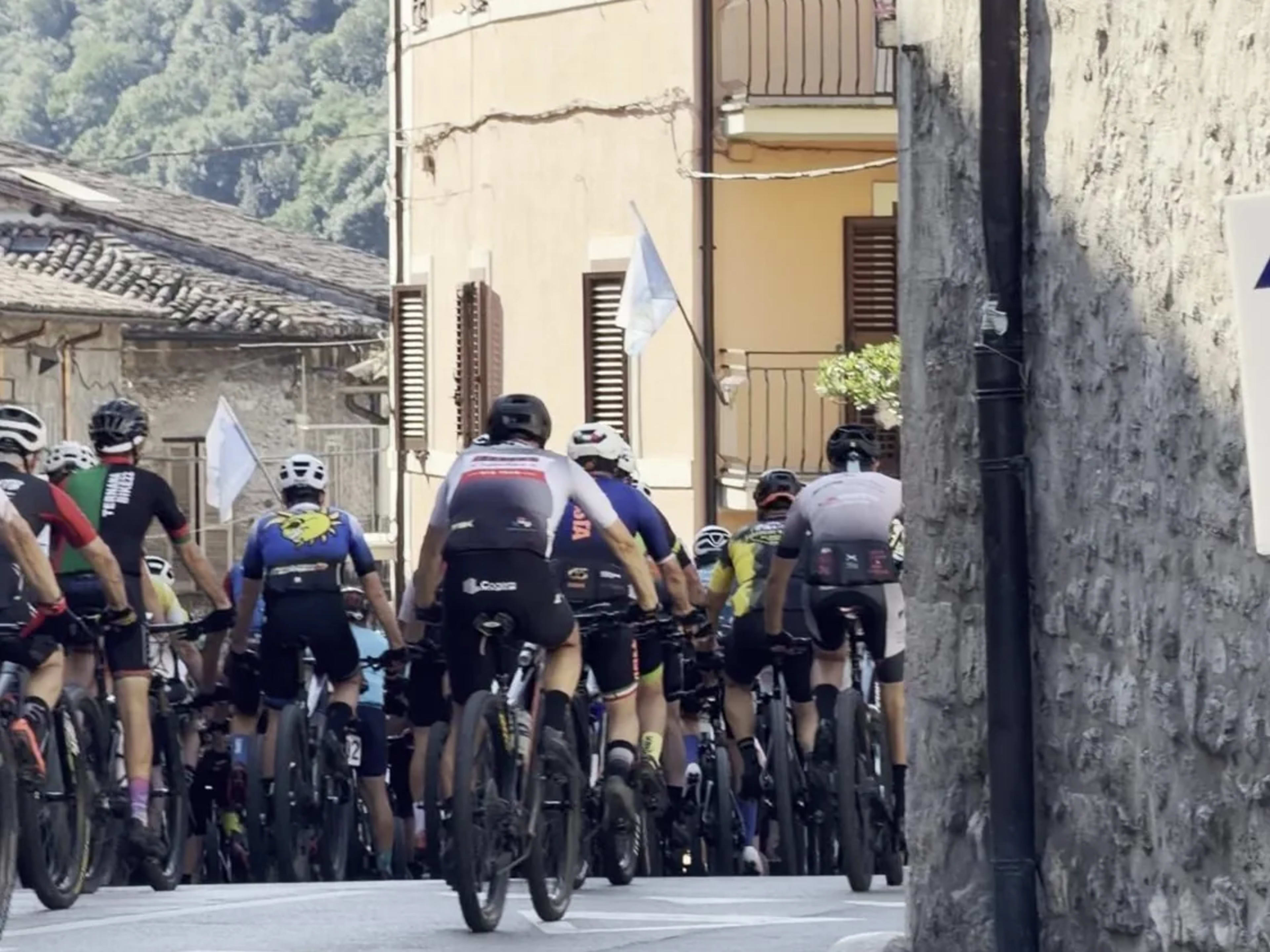 Gruppo di atleti pedala in fila lungo una via stretta della Valnerina