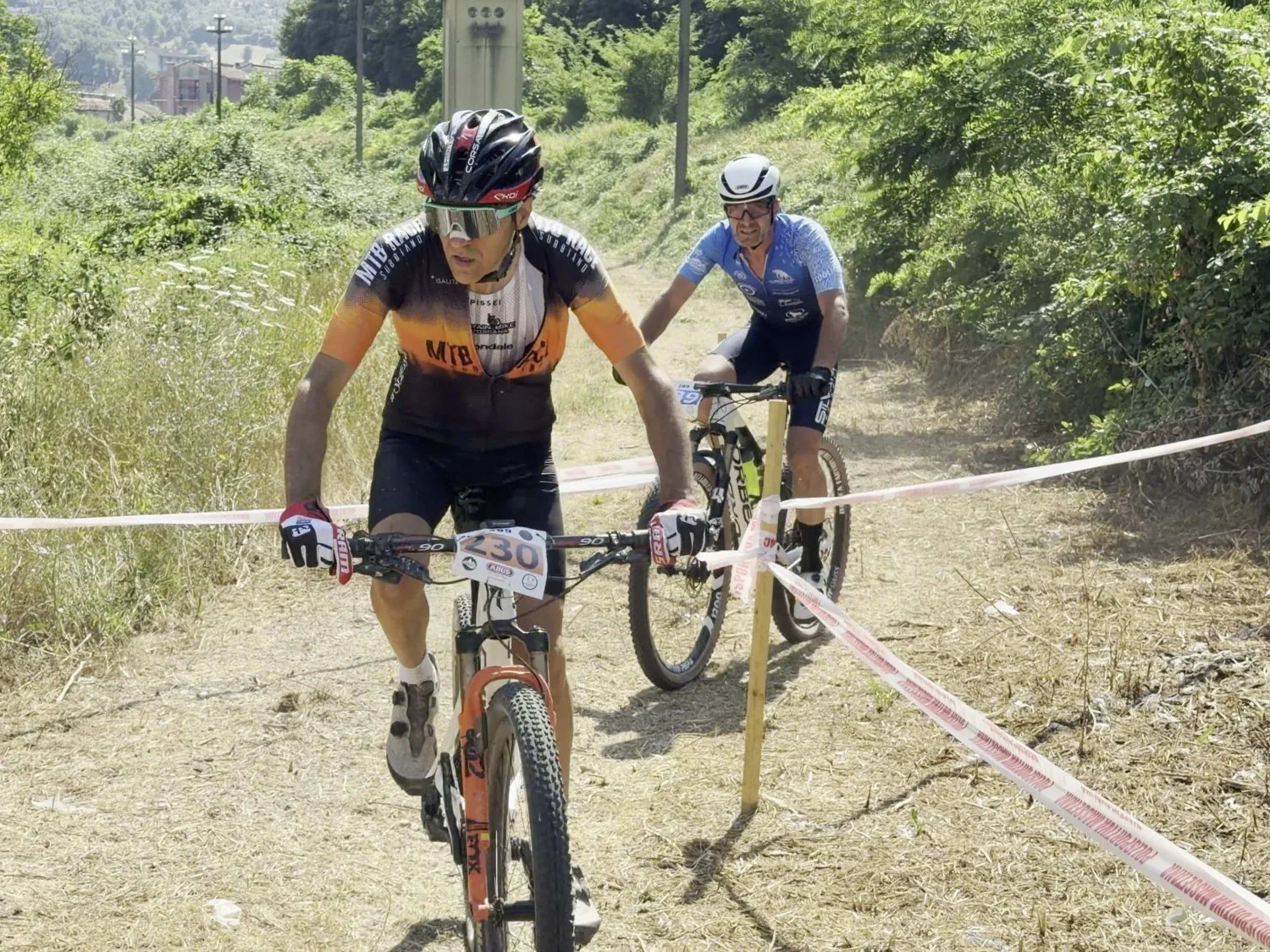 Mountain biker affronta un tratto di campagna inseguito da un avversario