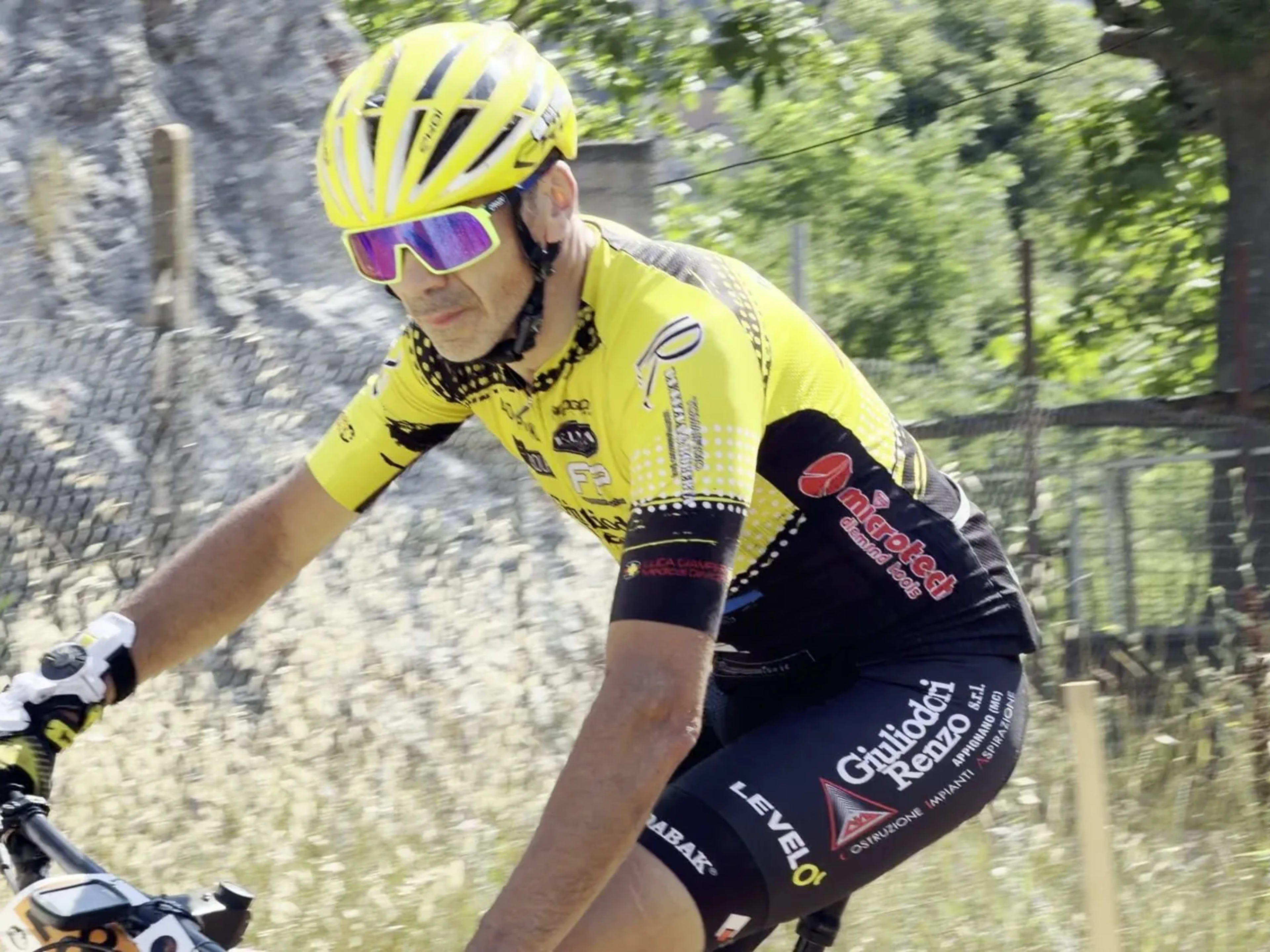 Biker in maglia gialla pedala concentrato sul tracciato di gara