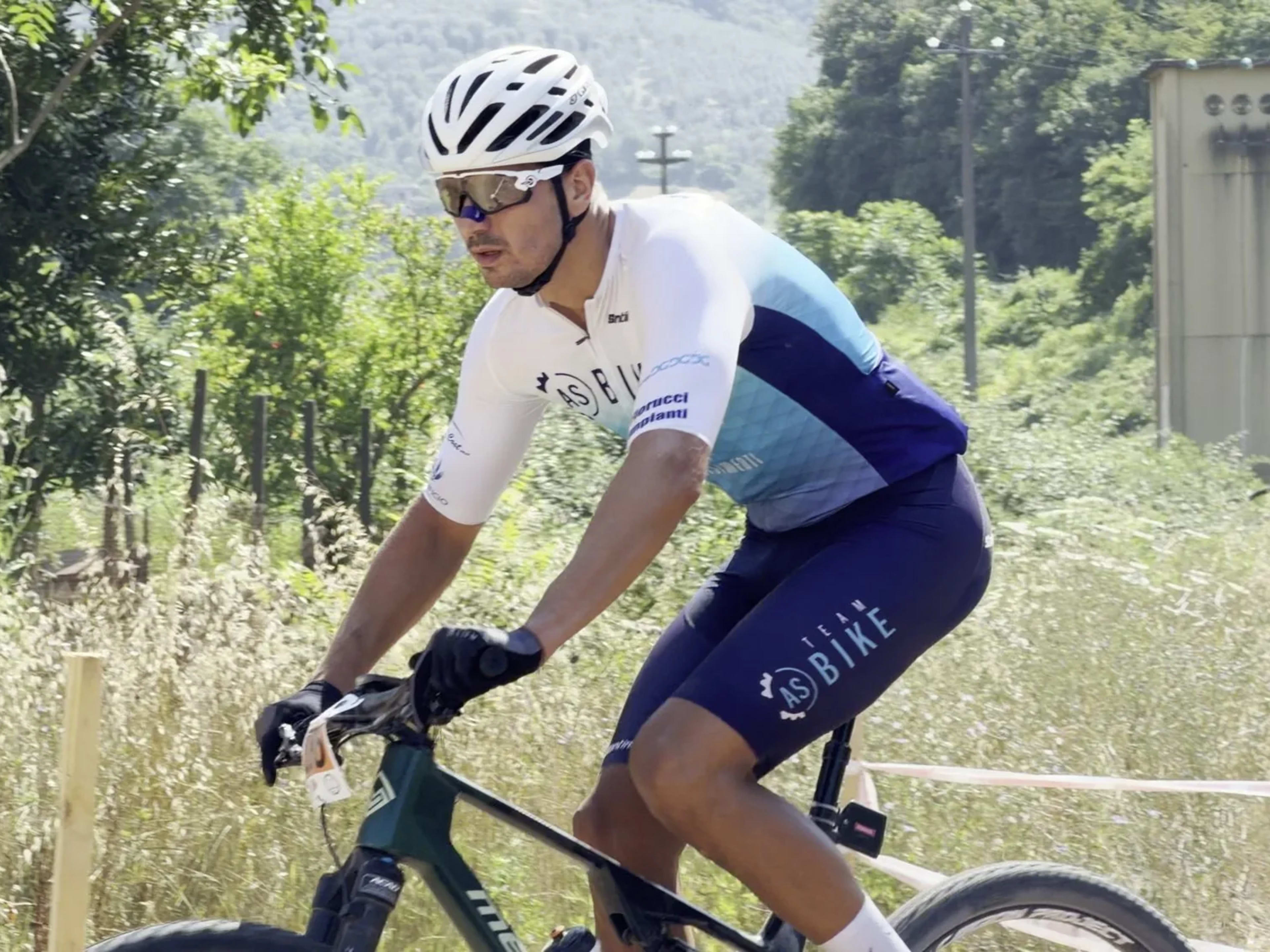 Mountain biker pedala su sterrato tra l'erba alta della Valnerina