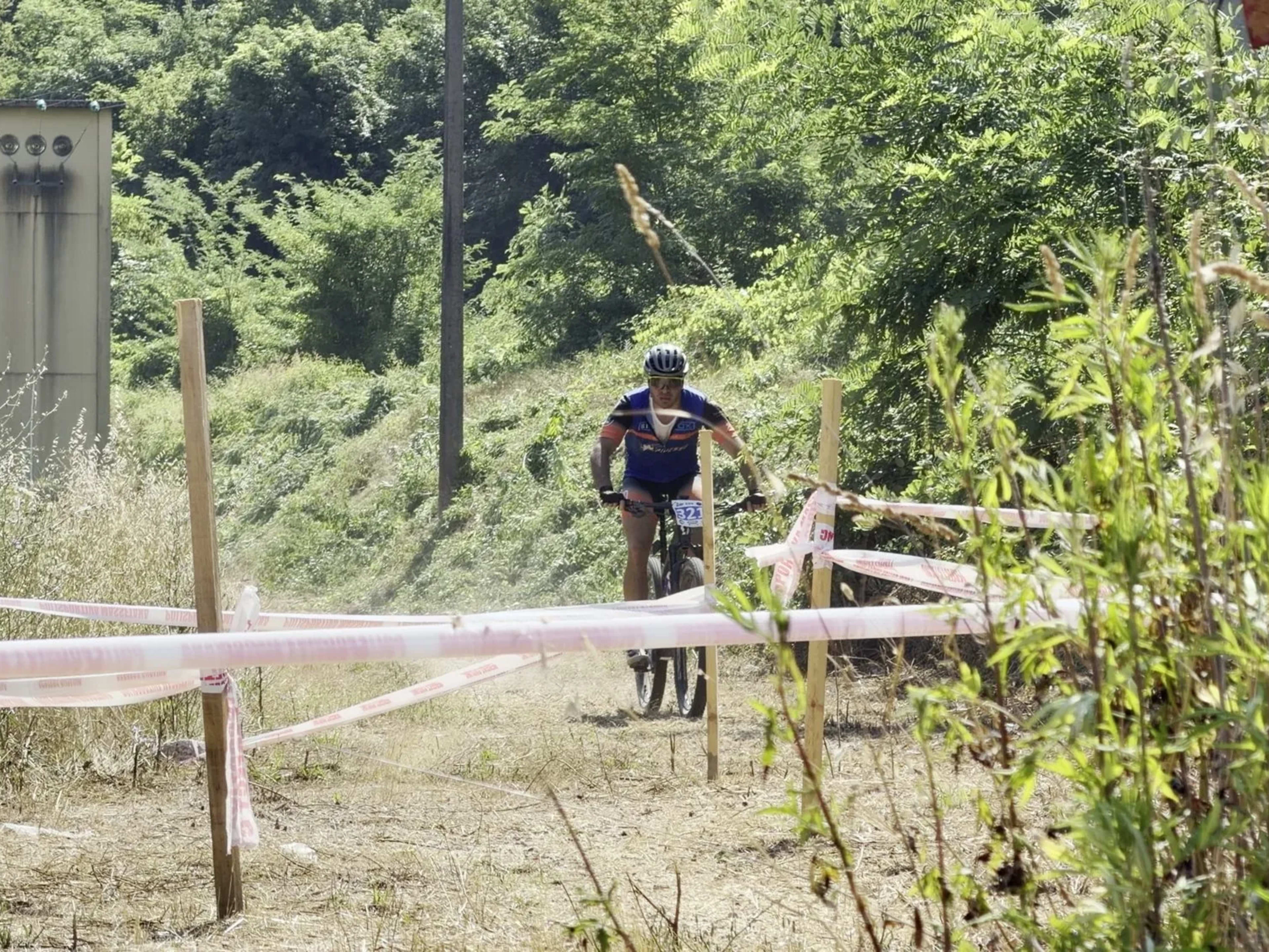 Biker isolato pedala sul tracciato tra la fitta vegetazione umbra