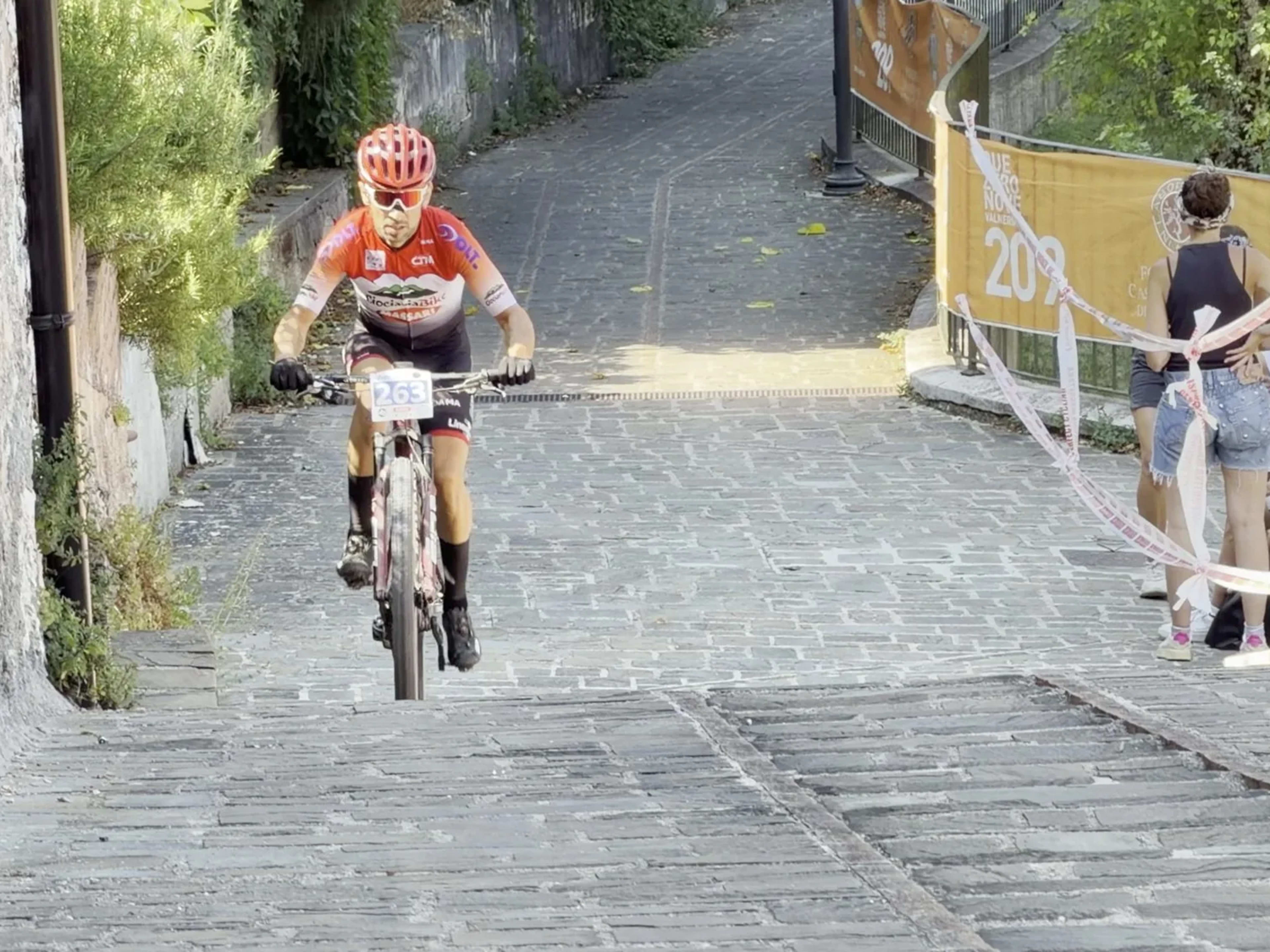 Biker in salita sull'acciottolato sotto lo sguardo degli spettatori