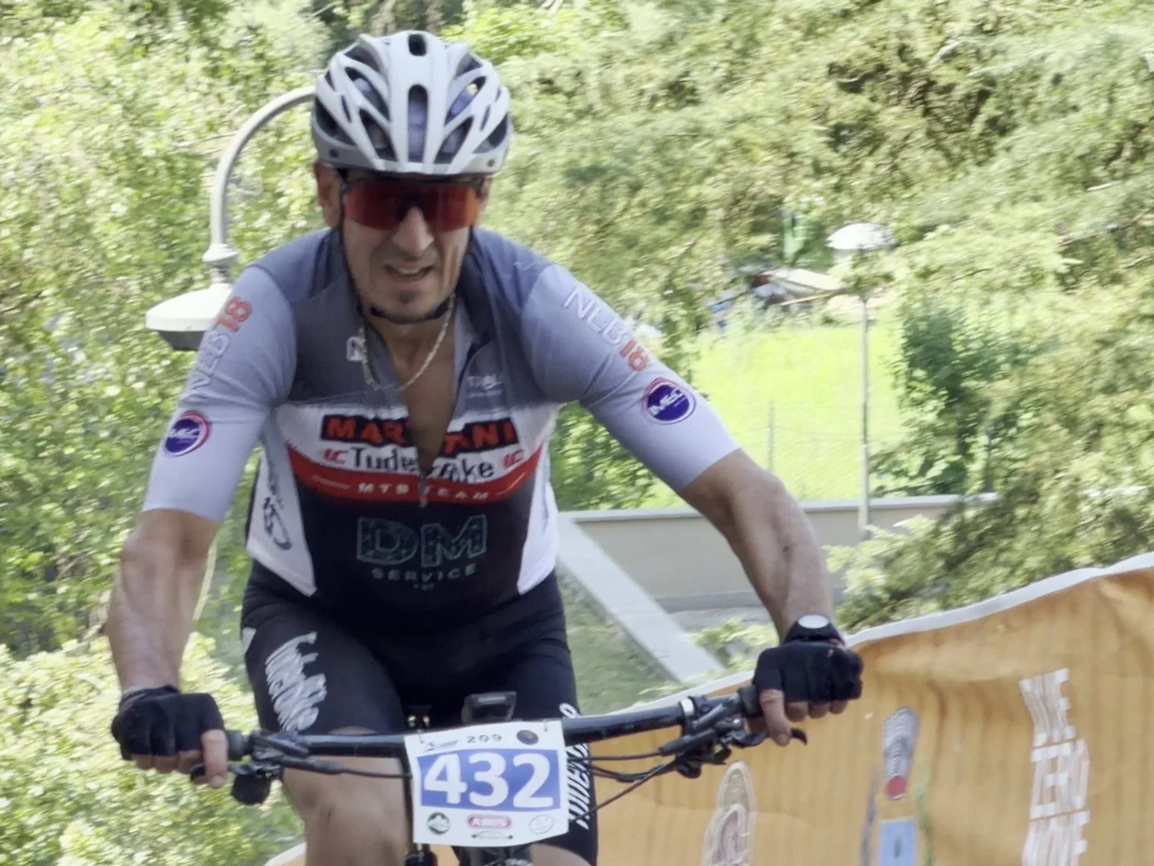 Primo piano di biker in maglia Marathon impegnato lungo le transenne