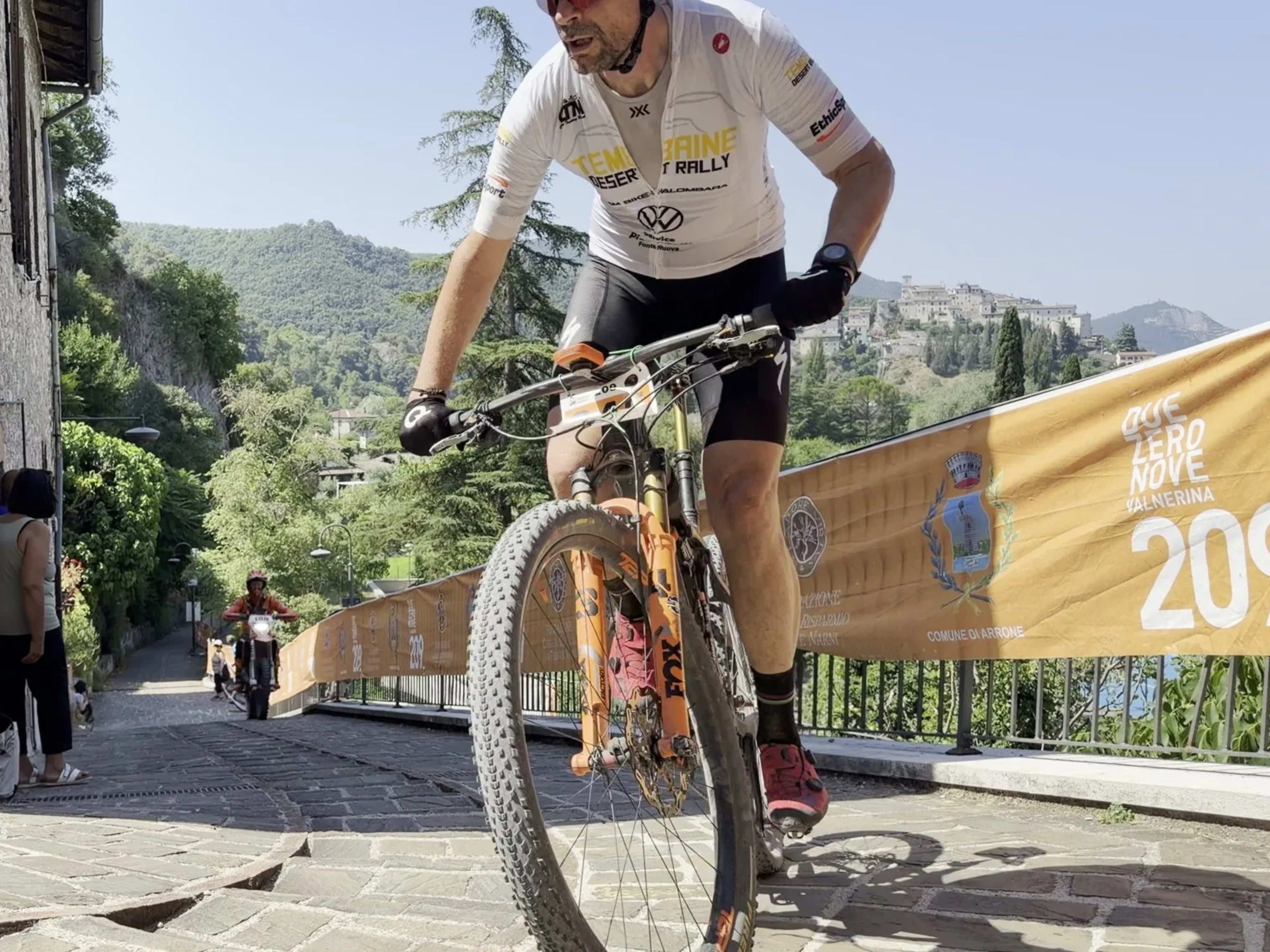 Atleta MTB impegnato nella discesa tecnica sul selciato del centro storico