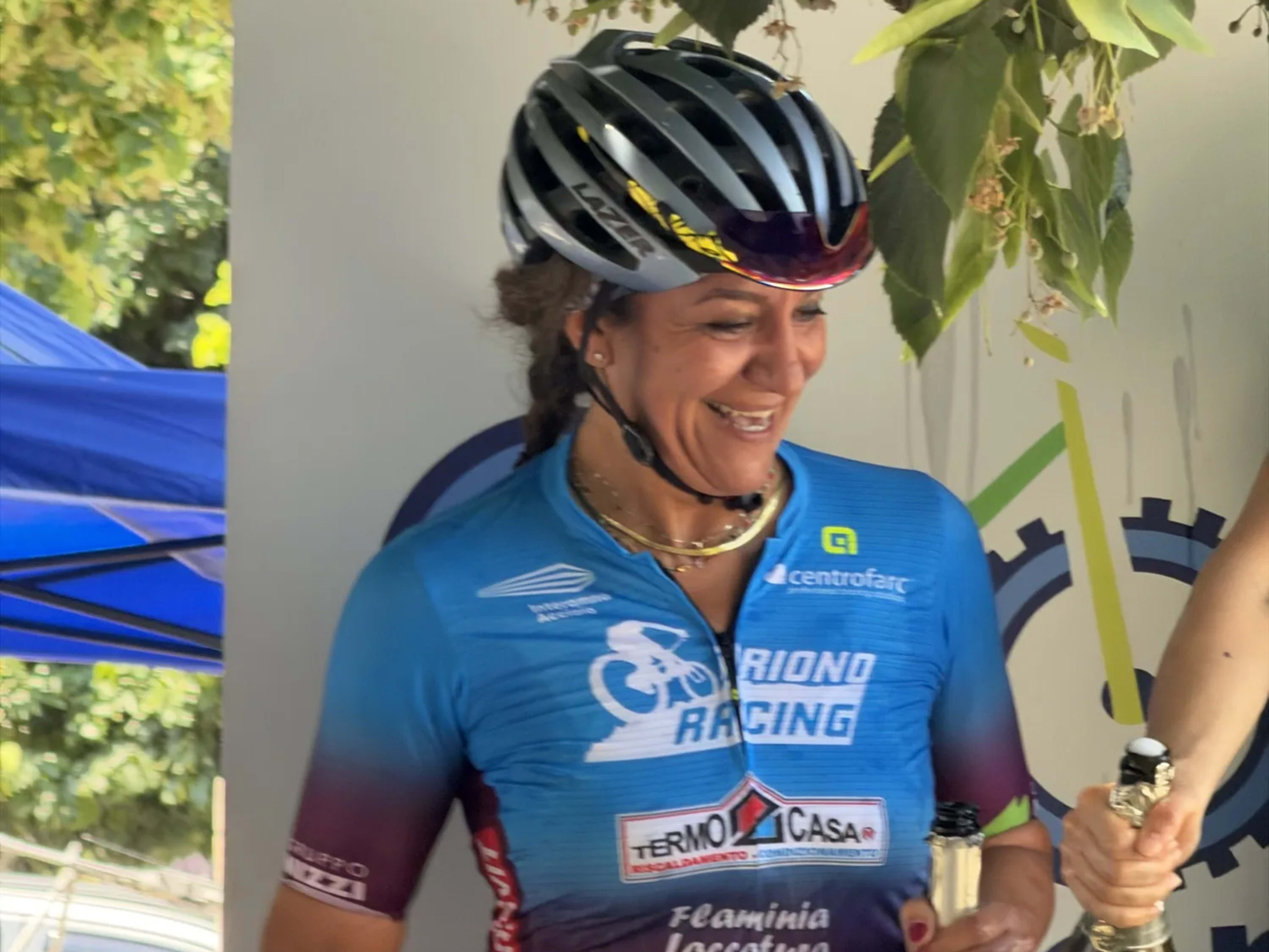 Biker premiata sorride con la bottiglia di spumante in mano