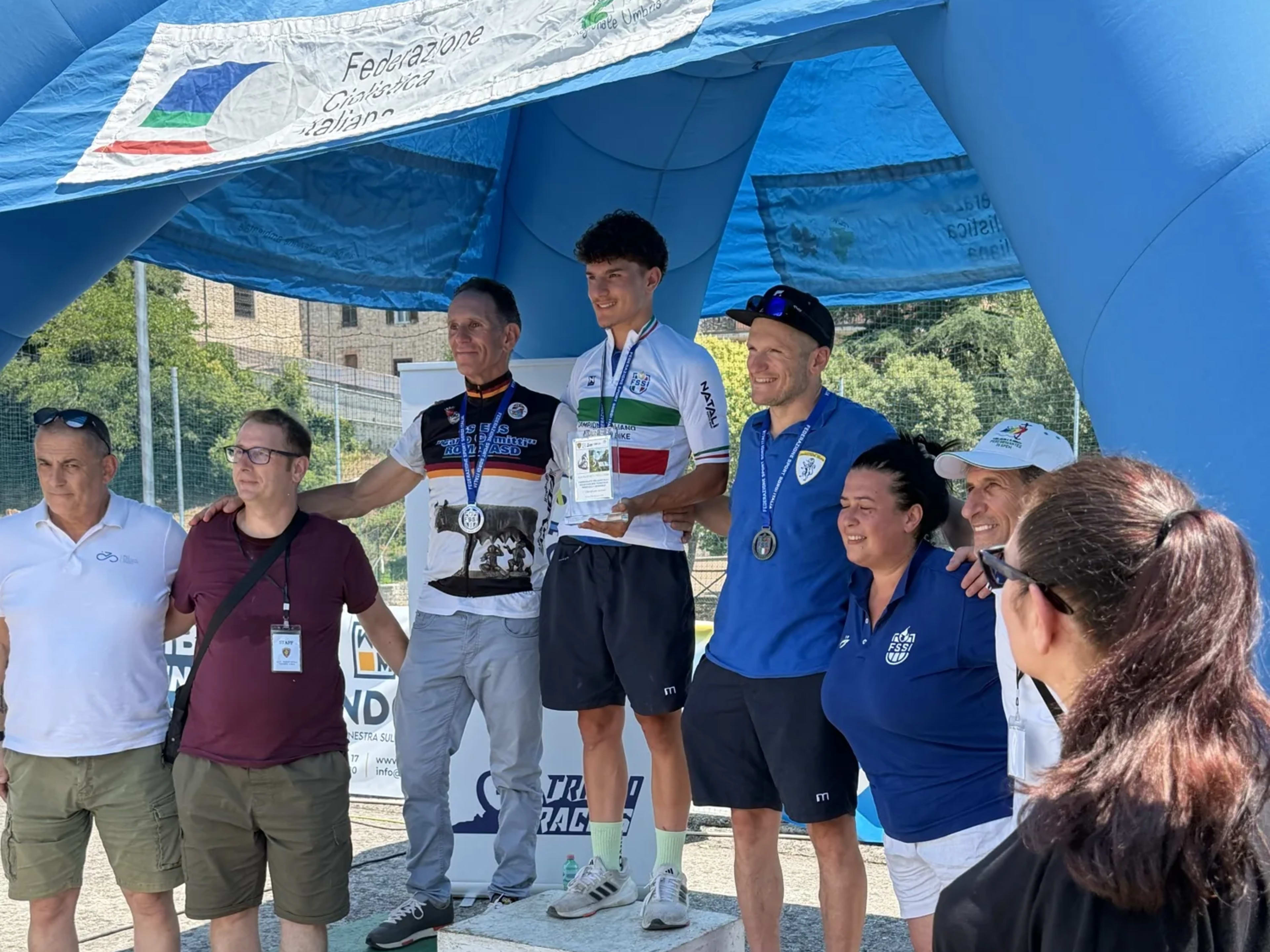 Premiazione di un giovane biker tra applausi e foto sotto l'arco gonfiabile