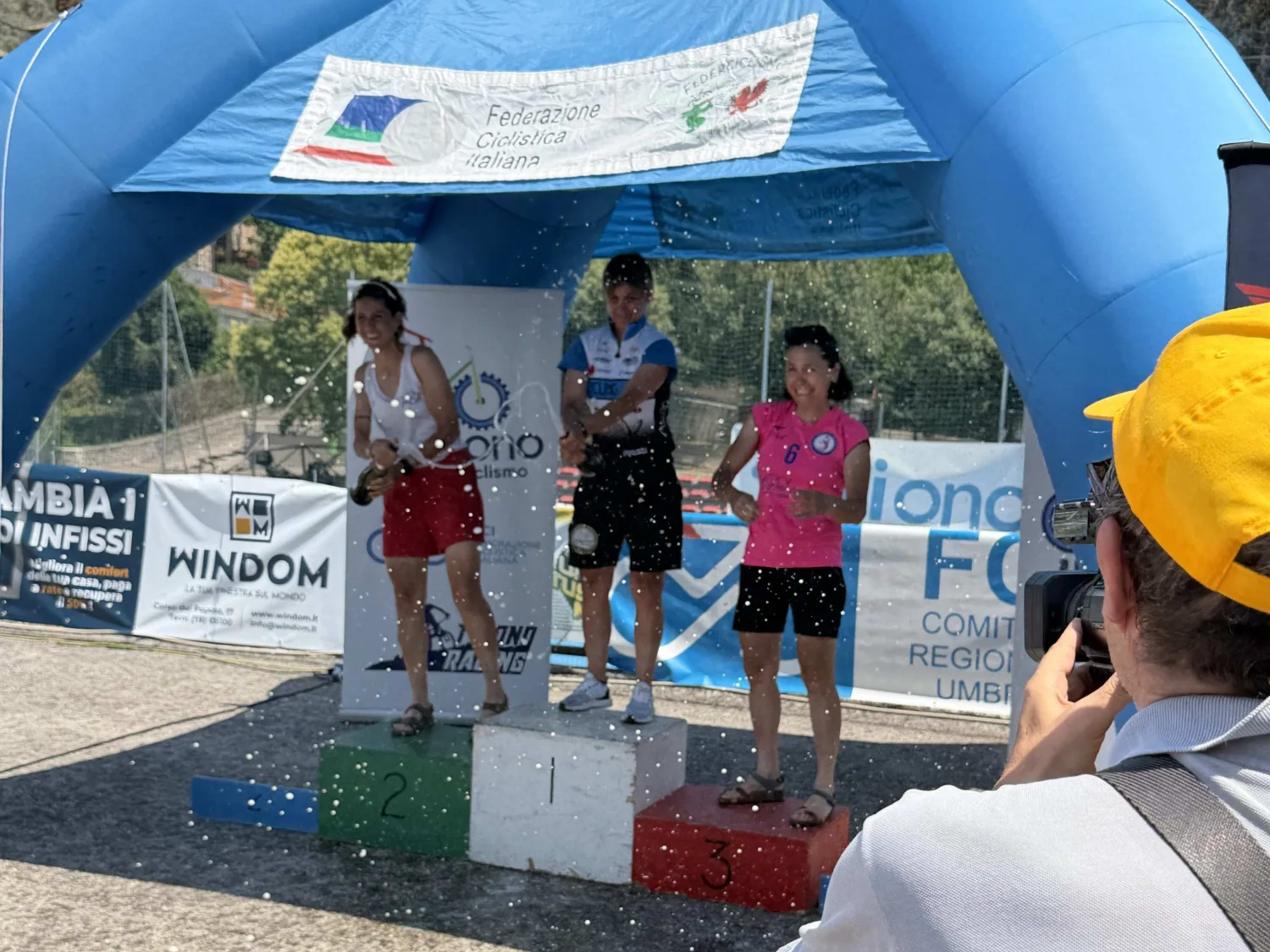 Atlete sul podio brindano con lo spumante durante la premiazione