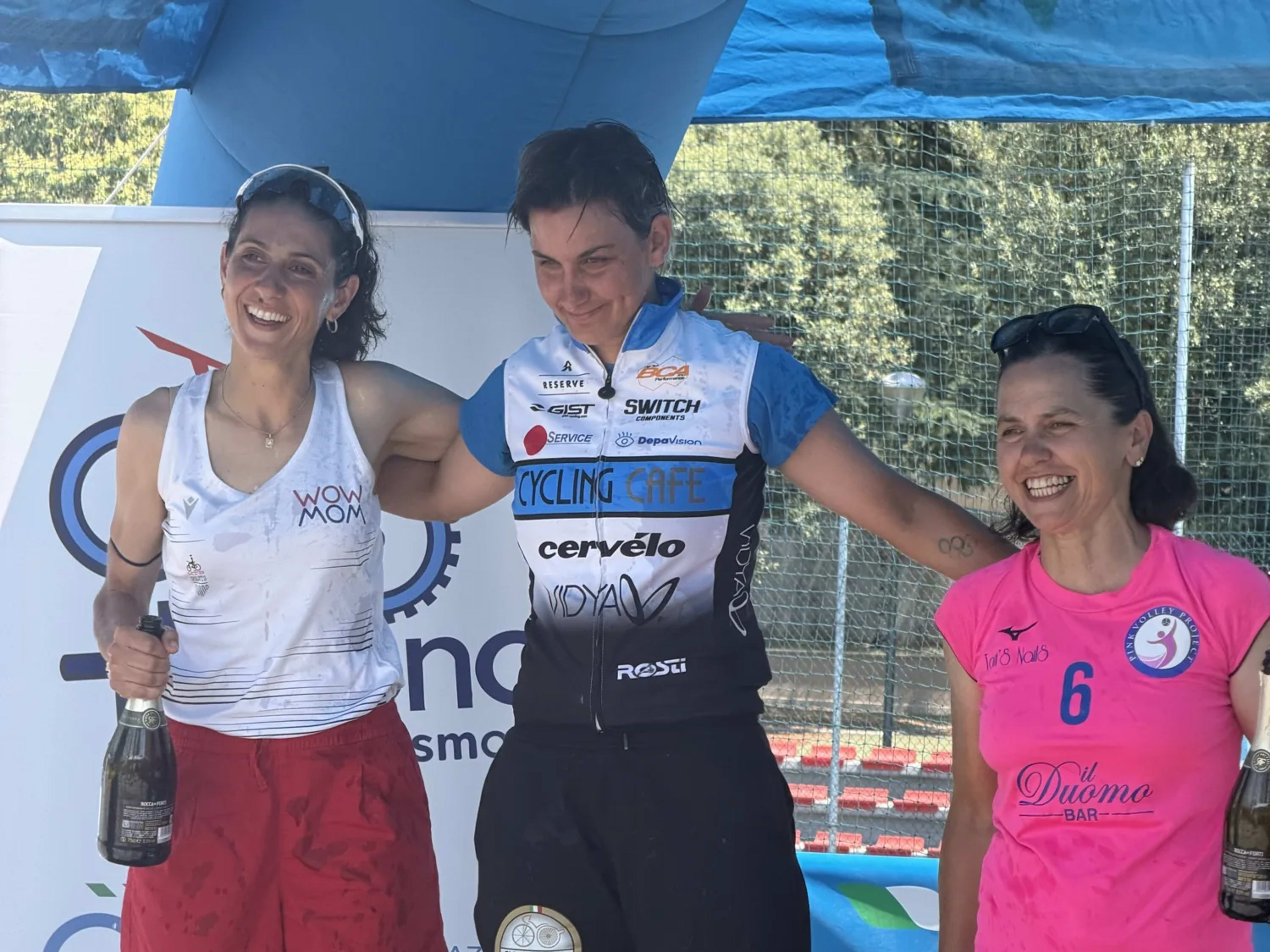 Podio femminile in festa con spumante durante la cerimonia di premiazione