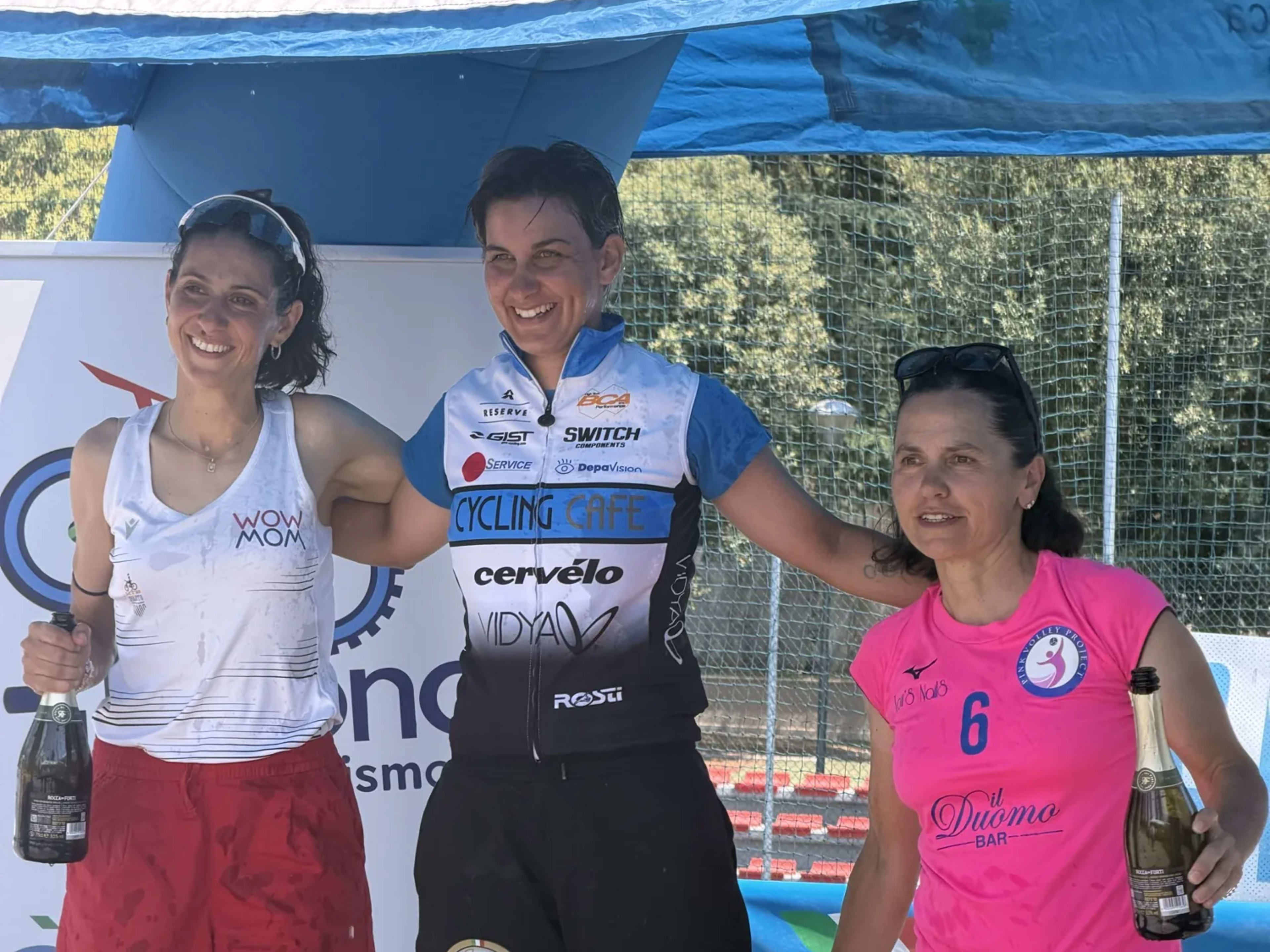 Tre atlete sorridenti sul podio con lo spumante a fine gara